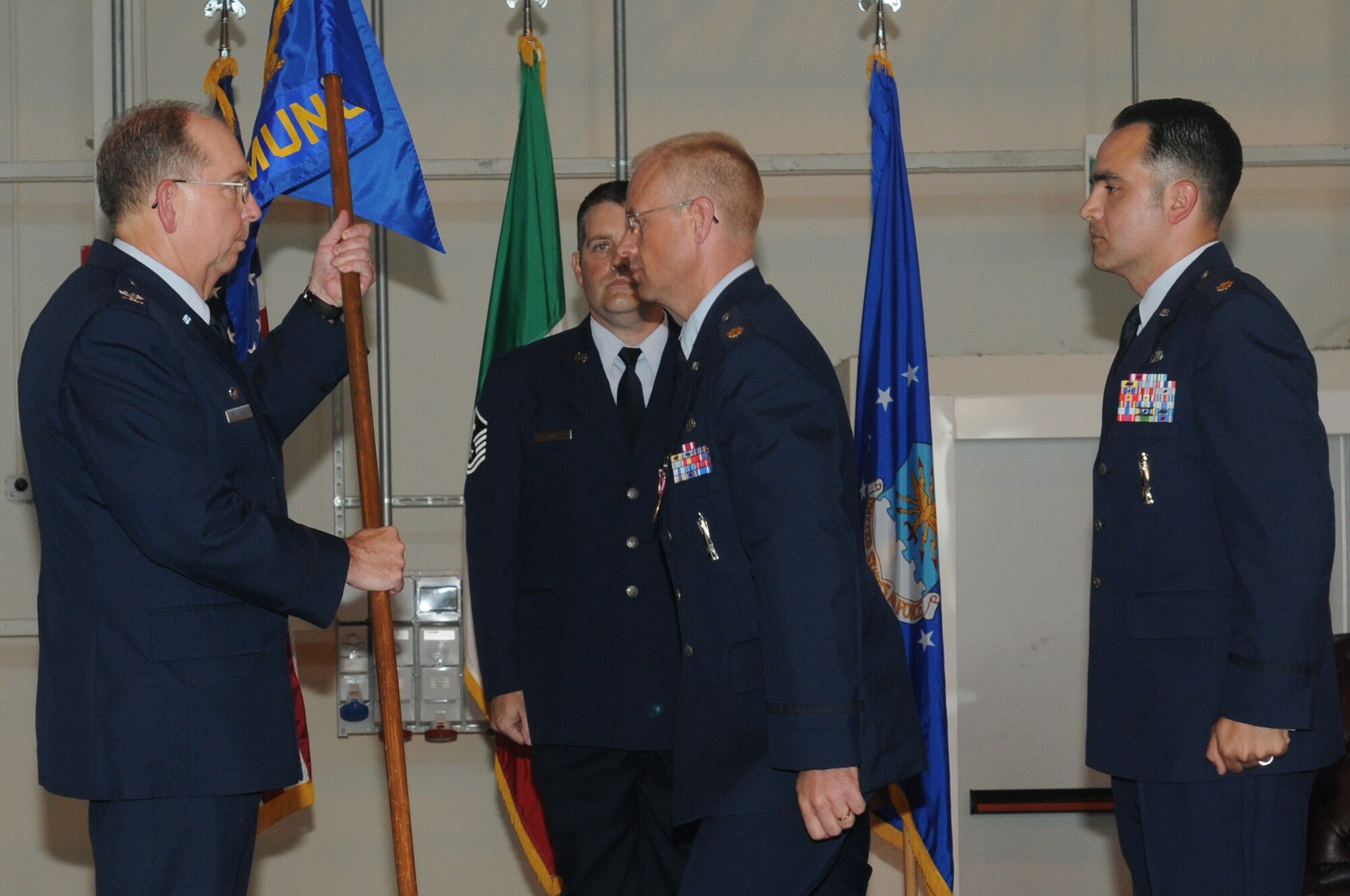 Maj. Michael W. Donahue II relinquishes the 31st Munitions Squadron flag to Col. Dennis W. Shumaker, 31st Maintenance Group commander, as Major Jason F. Vattioni looks on during the 31st MUNS change of command ceremony July 9 at Hangar 3. Major Donahue and his family are heading to Barksdale Air Force Base, La., where he will be joining the Inspector General Battlestaff. (U.S. Air Force photo/Airman LaVel Sterling)