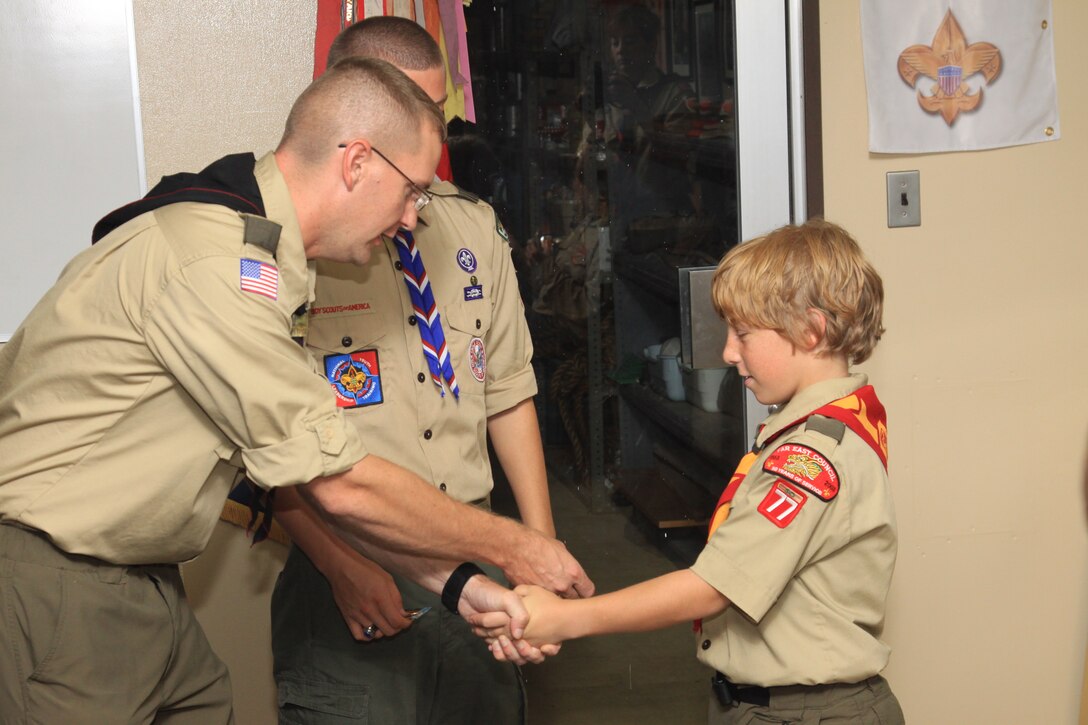Boy Scouts of America Far East Council Troop 77 Assistant Scout Master Brandon Fisher takes the tenderfoot badge from Eagle Scout Tevor Wentling, 17, to promote Tenderfoot David Rasmussen, 11, from the rank of scout to his current rank July 12. Rasmussen was promoted for his outstanding teamwork and performance during the troop’s summer camp.