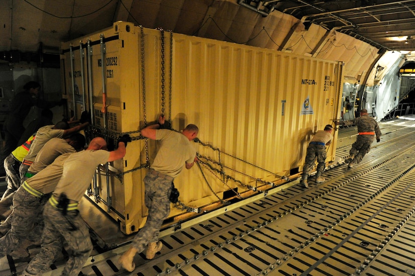 CAMP MARMAL, MAZAR-I-SHARIF, Afghanistan – Airmen from the 621st Contingency Response Wing based at Joint-Base McGuire-Dix-Lakehurst, NJ, push a prefabricated shelter facility from a C-5B Galaxy onto a waiting 60k cargo loader at Camp Marmal, Afghanistan July 1. Thousands of tons of supplies have been processed in the past few weeks by teams of CRW Airmen as forces called up by the presidentially-directed surge of manpower and equipment have been arriving into Afghanistan. (U.S. Air Force photo/Tech. Sgt. Parker Gyokeres/released)