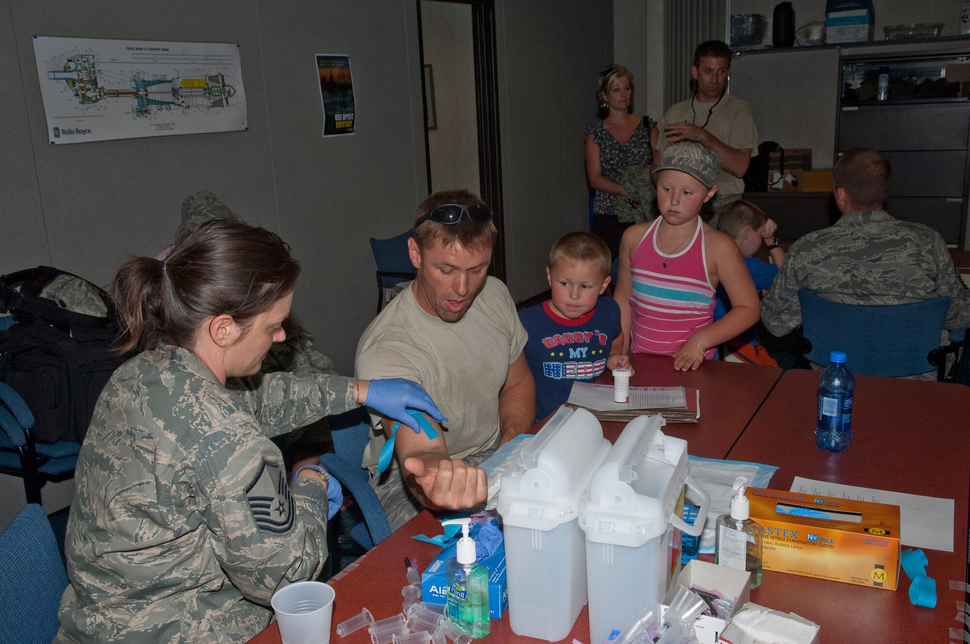 An Airman gets his blood drawn after returning from a combat zone as his family watches on July 11, 2010 at the St. Paul Air National Guard base. The military cargo aircraft and about twenty Airmen are the first in a series of returns from Afghanistan during July for the 133rd Airlift Wing in 2010. USAF official photo by Senior Master Sgt. Mark Moss