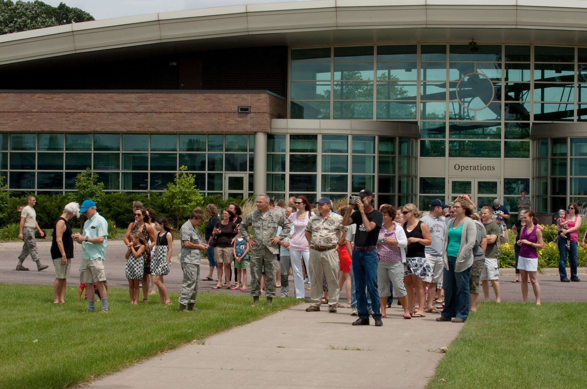 A crowd of friends and family on the Minnesota Air National Guard base watches a C-130 "Hercules" perform a fly-by and then land at the Minneapolis-St. Paul International airport on July 11, 2010 after returning from a tour in Afghanistan. The military cargo aircraft and about twenty Airmen are the first in a series of returns during July for the 133rd Airlift Wing in 2010. USAF official photo by Senior Master Sgt. Mark Moss