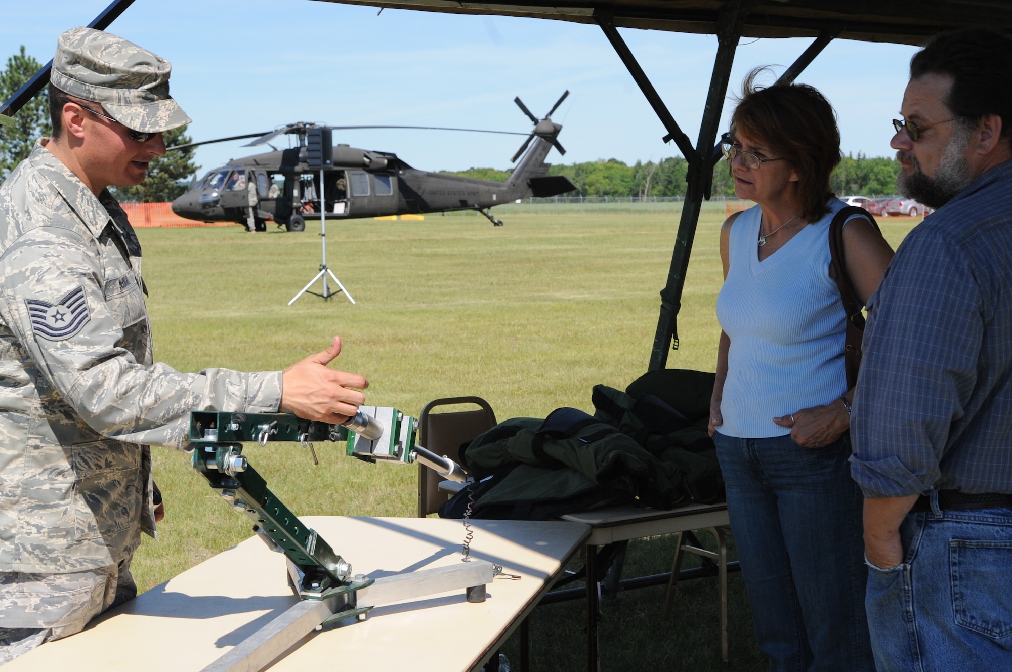 Tech. Sgt. Daniel McKnight, 5th Civil Engineer Squadron, shows a Percussion Actuator Neutralizer Disrupter to attendees of the Cavalier Air Force Station open house July 10. A PAN Disrupter is used to disarm improvised explosive devises. This instrument is used to shoot an object at an IED in order to disrupt the electronic components of the IED. The open was held as a way for people within the local community to learn about the mission and capabilities of Cavalier AFS as well as the Air Force and military in general. (U.S. Air Force photo by 1st Lt. Anastasia Wasem) 