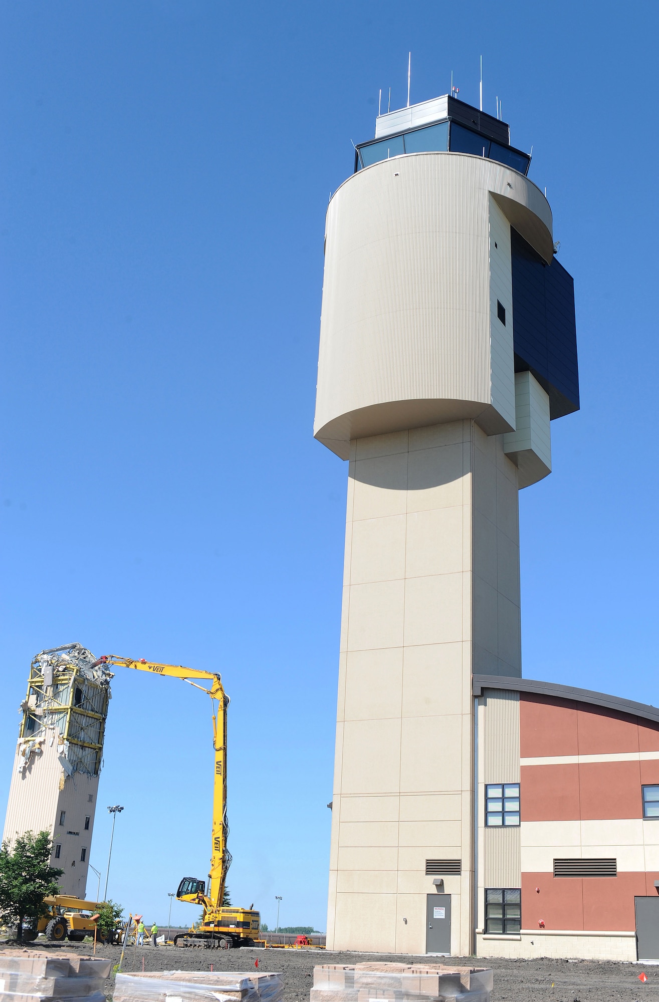 Contractors use heavy equipment to tear down the old air traffic control tower next to a new state-of-the-art control tower July 9, on Grand Forks Air Force Base, N.D.  The old tower has been replaced with a new $13 million co-located air traffic control facility. The new facility will provide space to expand ATC capabilities to support future missions. (U.S. Air Force photo/Staff Sgt. Suellyn F. Nuckolls)