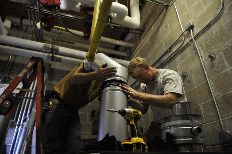 MOODY AIR FORCE BASE, Ga.-- Chris Gaskins and Ron Skinner 23rd Civil Engineer Squadron heating, ventilation, air conditioning and refrigeration technician, assembles a boiler stack here July 7. The previous boiler stack had rusted due to wear and tear. (U.S. Air Force photo by Staff Sgt. Schelli Jones/RELEASED)