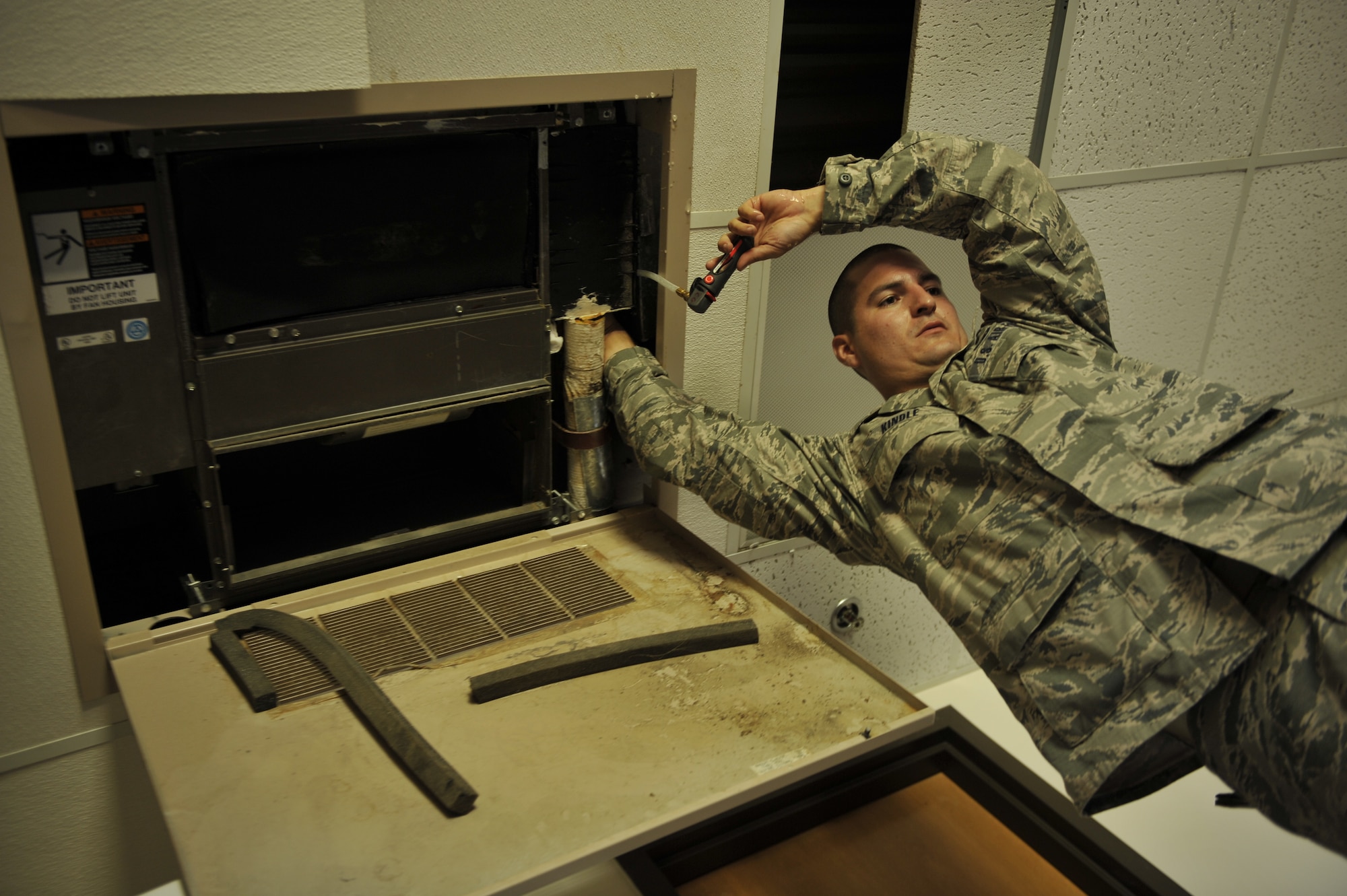MOODY AIR FORCE BASE, Ga.-- Senior Airman Steven Kindle, 23rd Civil Engineer Squadron heating, ventilation, air conditioning and refrigeration journeyman, cleans out a drain line in a dormitory room here July 7.  The drain line requires cleaning because air condition units leak due to sludge build up. (U.S. Air Force photo by Staff Sgt. Schelli Jones/RELEASED)