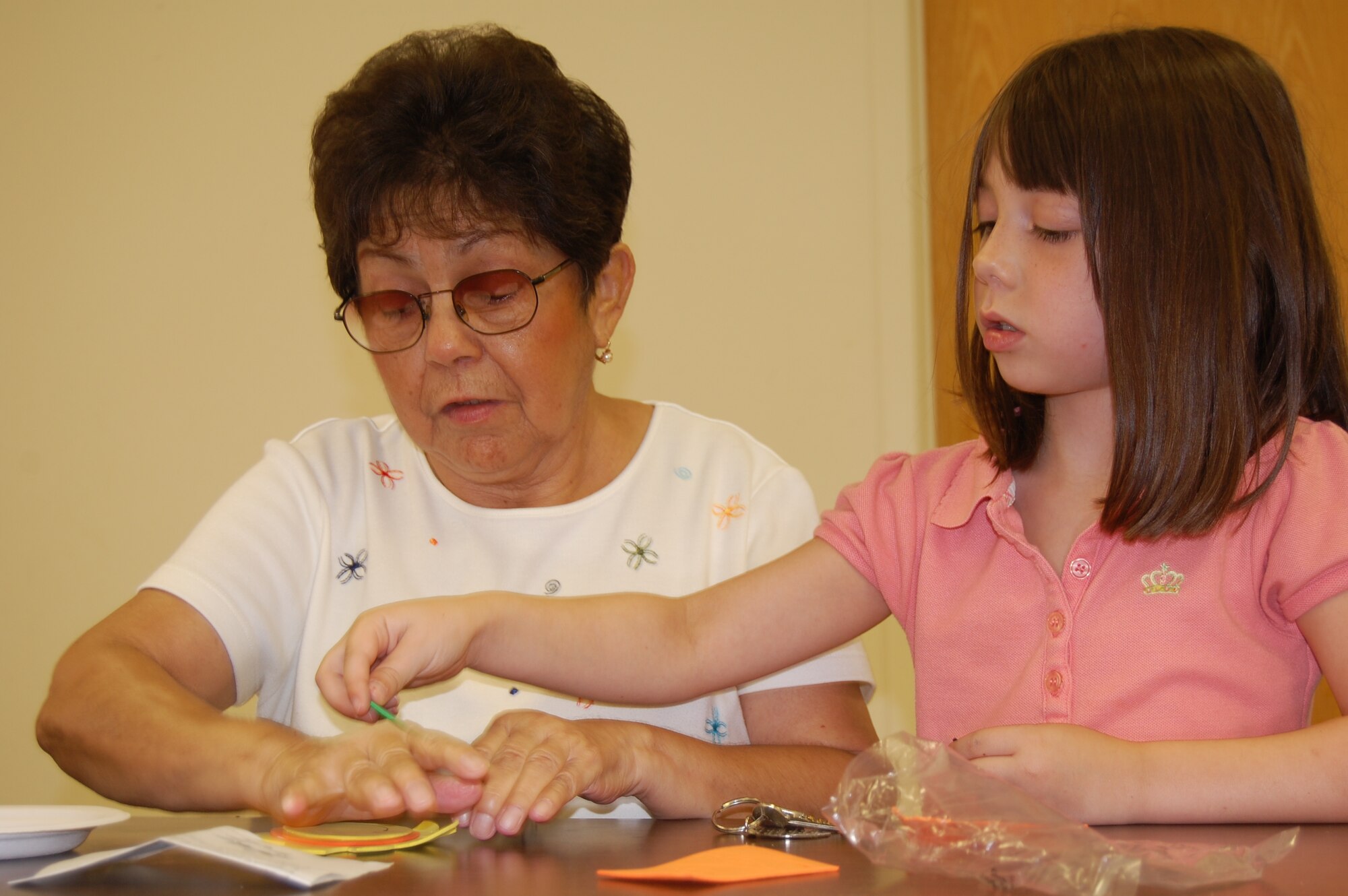 LAUGHLIN AIR FORCE BASE, Texas – Keira, Laughlin School Age participant, helps Maria Rodriguez, resident at Del Rio Rotary Village, assemble a foam arts and crafts project July 8. Keira and 20 other youth members of the School Age program visited residents of the Del Rio Rotary Village as part of their community service project. (U.S. Air Force Photo by Staff Sgt. Desiree Economides)