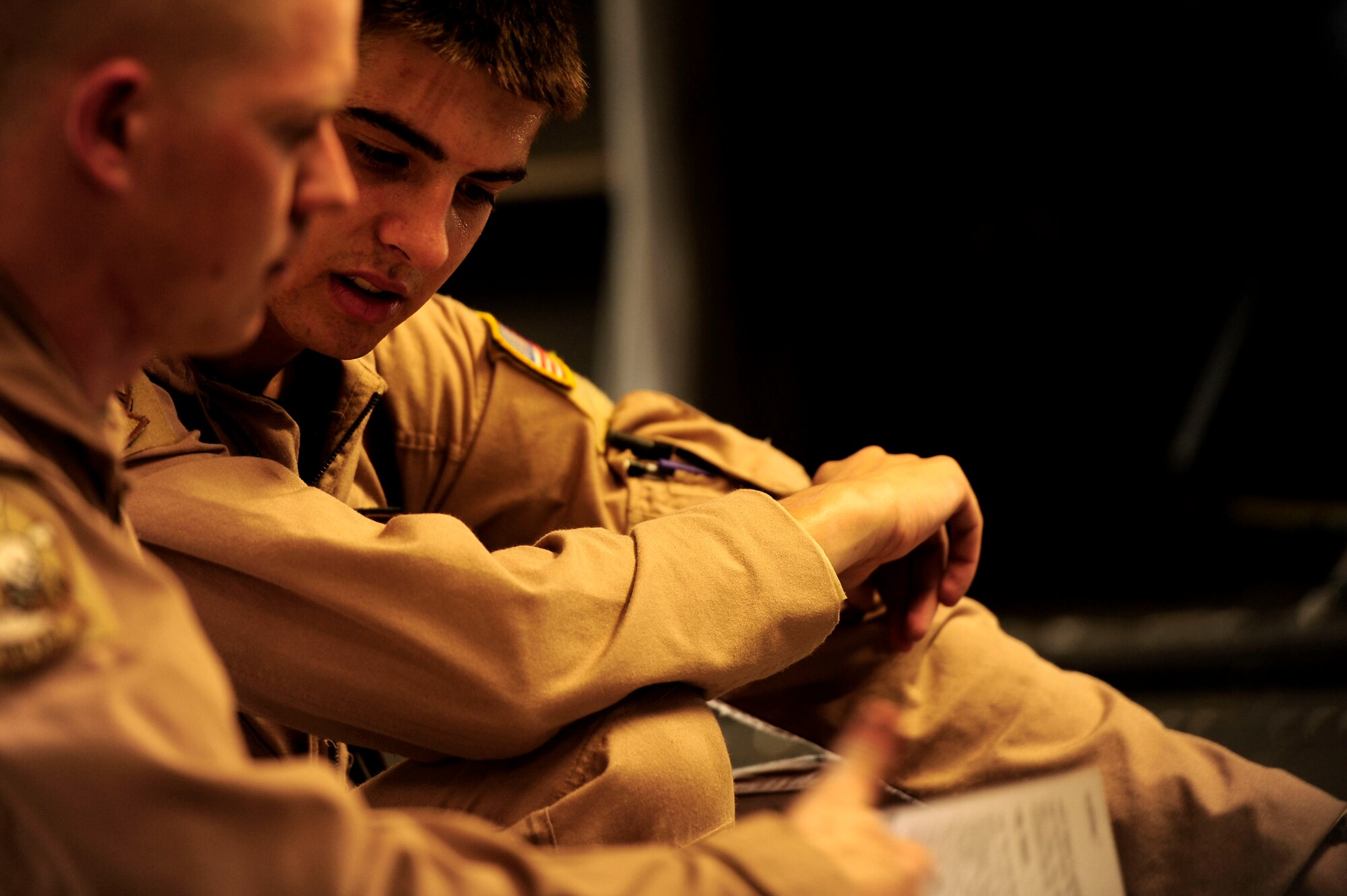 U.S. Air Force Airman First Class Brian Whitcomb, right, and A1C Tyler Hertzog both C-17 Globemaster III loadmasters assigned to the 816th Expeditionary Airlift Squadron, look over training manuals together for on the job training before a flying mission to Baghdad, Iraq, from an undisclosed location in Southwest Asia on July 6, 2010. (U.S. Air Force photo by Staff Sgt. Andy M. Kin / Released)