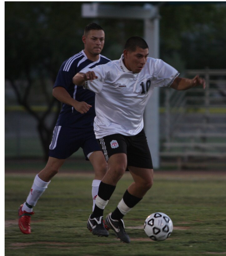 A player for the MCCES team, dribbles the ball down field during the Commanding General’s Intramural Soccer League Championship game against HQBN July 14 at Felix Field.