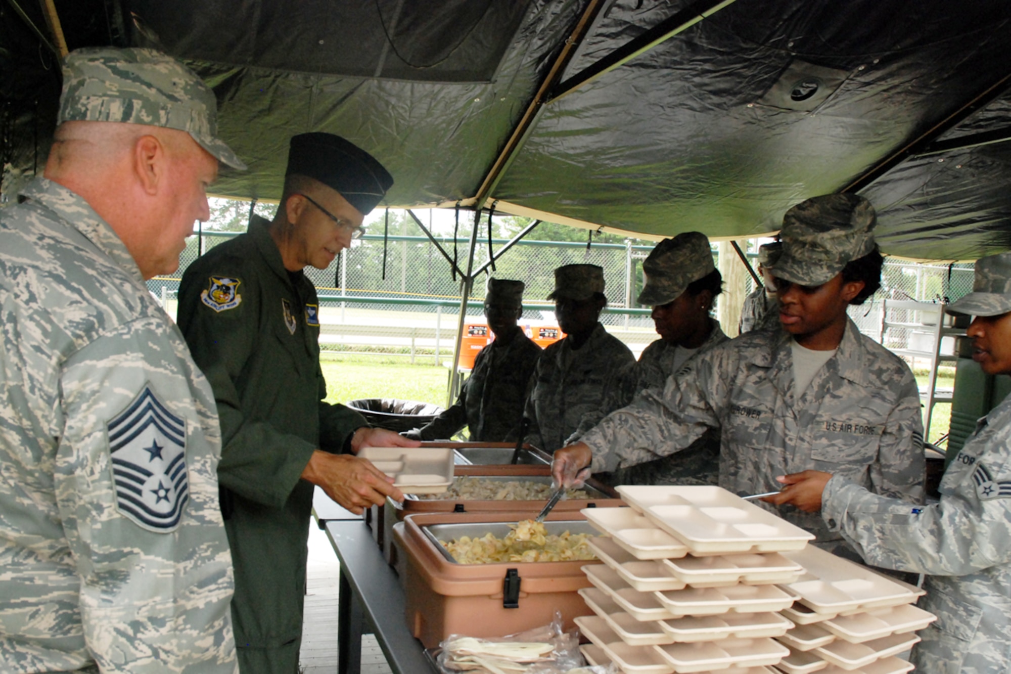 Col. Timothy E. Tarchick, commander, and Command Chief Master Sgt. John M. Anderson of the 94th Airlift Wing attend a luncheon prepared by the 94th Services Squadron during their quarterly Single Pallet Expeditionary Kitchen (SPEK) Training July 10 at Dobbins Lakeside Facility. The SPEK fits on a standardized load pallet, can be operated by as few as four Airmen, takes approximately four hours to set up and can be easily loaded on a C-130 aircraft. With the SPEK, Services personnel can provide 550 Airmen a hot meal minutes after setup (U.S. Air Force photo/Master Sgt. James Branch)