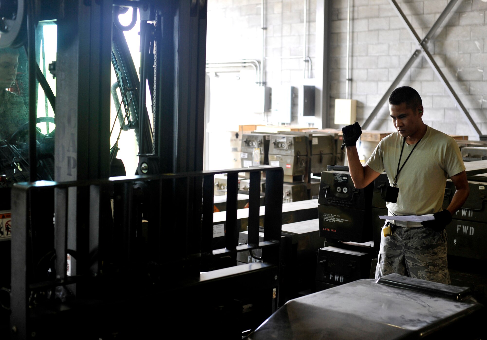 MISAWA AIR BASE, Japan -- Staff Sgt. Eric Frondozo, 35th Maintenance Squadron munitions systems specialist, marshals a fork-lift driver while lifting munitions July 13. The team cleared more than 11,000 square feet of space after disposing the unneeded munitions. (U.S. Air Force photo/Staff Sgt. Chad C. Strohmeyer)