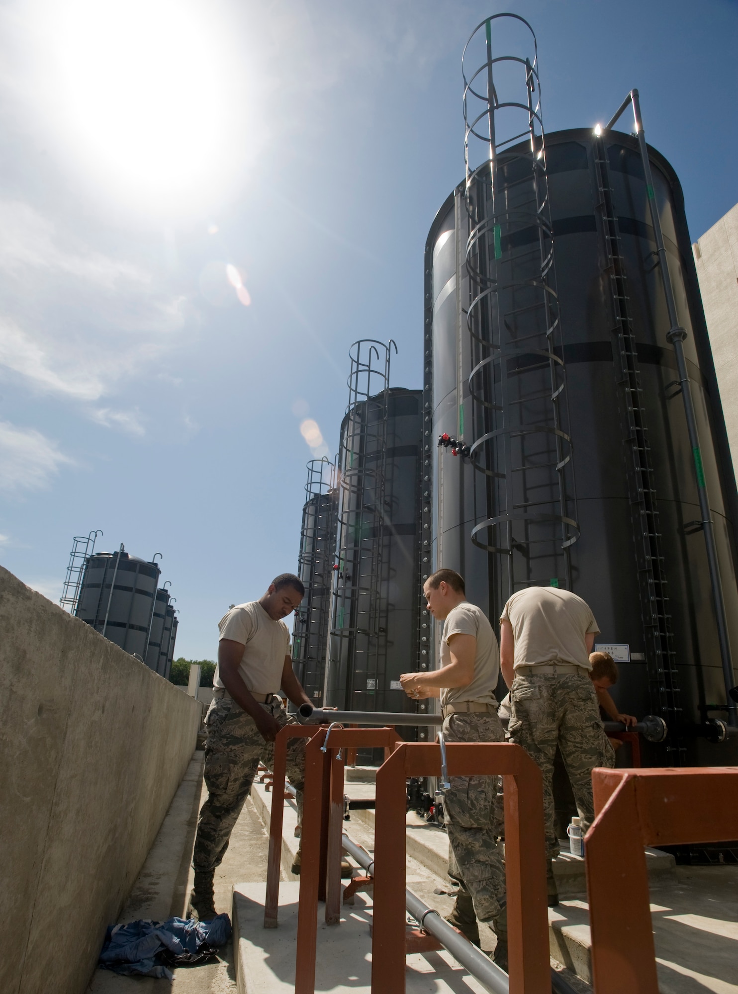 MISAWA AIR BASE, Japan -- Airman First Class Tony Rhodes, Airman Matthew Rieman and Airman First Class Jessie Hundley sand and glue PVC pipes together that are attached to tanks, July 13. The 35th Civil Engineer Squadron water and fuels systems maintenance flight has worked intermittently over the past six months on finalizing four new potassium acetate, de-icer tanks. (U.S. Air Force photo by Staff Sgt Araceli Alarcon) 