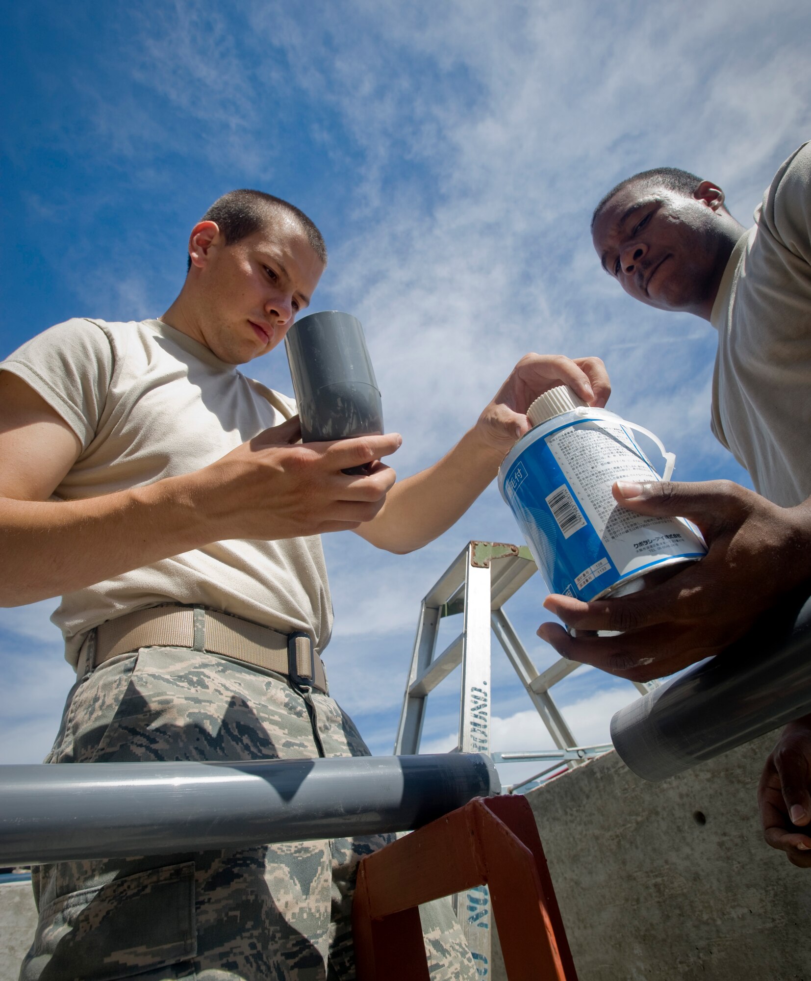 MISAWA AIR BASE, Japan -- Airman First Class Tony Rhodes and Airman Matthew Rieman, 35th Civil Engineer Squadron, water and fuels systems maintenance, place glue on the inside an elbow piece of  PVC, July 13. The piping is part of a six months project, which includes the installation of four new potassium acetate de-icer tanks, costing an estimated $250,000. (U.S. Air Force photo by Staff Sgt Araceli Alarcon) 