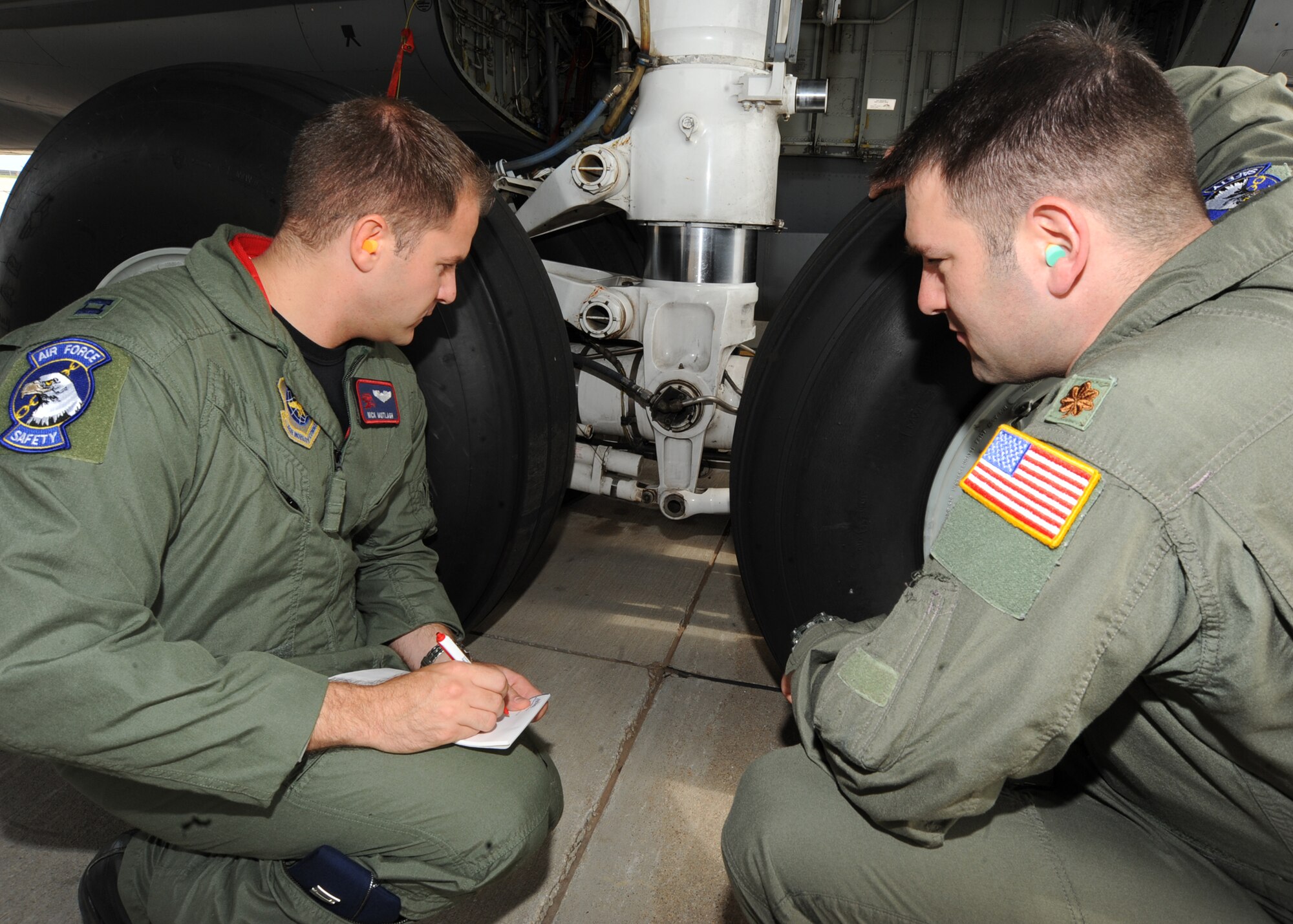 Capt. Nick Motlagh and Maj. Jeremy Fischman, 22nd Air Refueling Wing flight safety officers, take notes as they inspect the landing gear system of a KC-135 Stratotanker June 16, 2010, McConnell Air Force Base, Kan.  The flight safety program investigates aircraft mishaps and makes recommendations to wing leadership on how to prevent future accidents.  The base’s flight safety encompasses programs such as, the bird and wildlife aircraft strike hazard and the Wichita mid-air collision avoidance.  (U.S. Air Force photo/ Senior Airman Maria Ruiz)