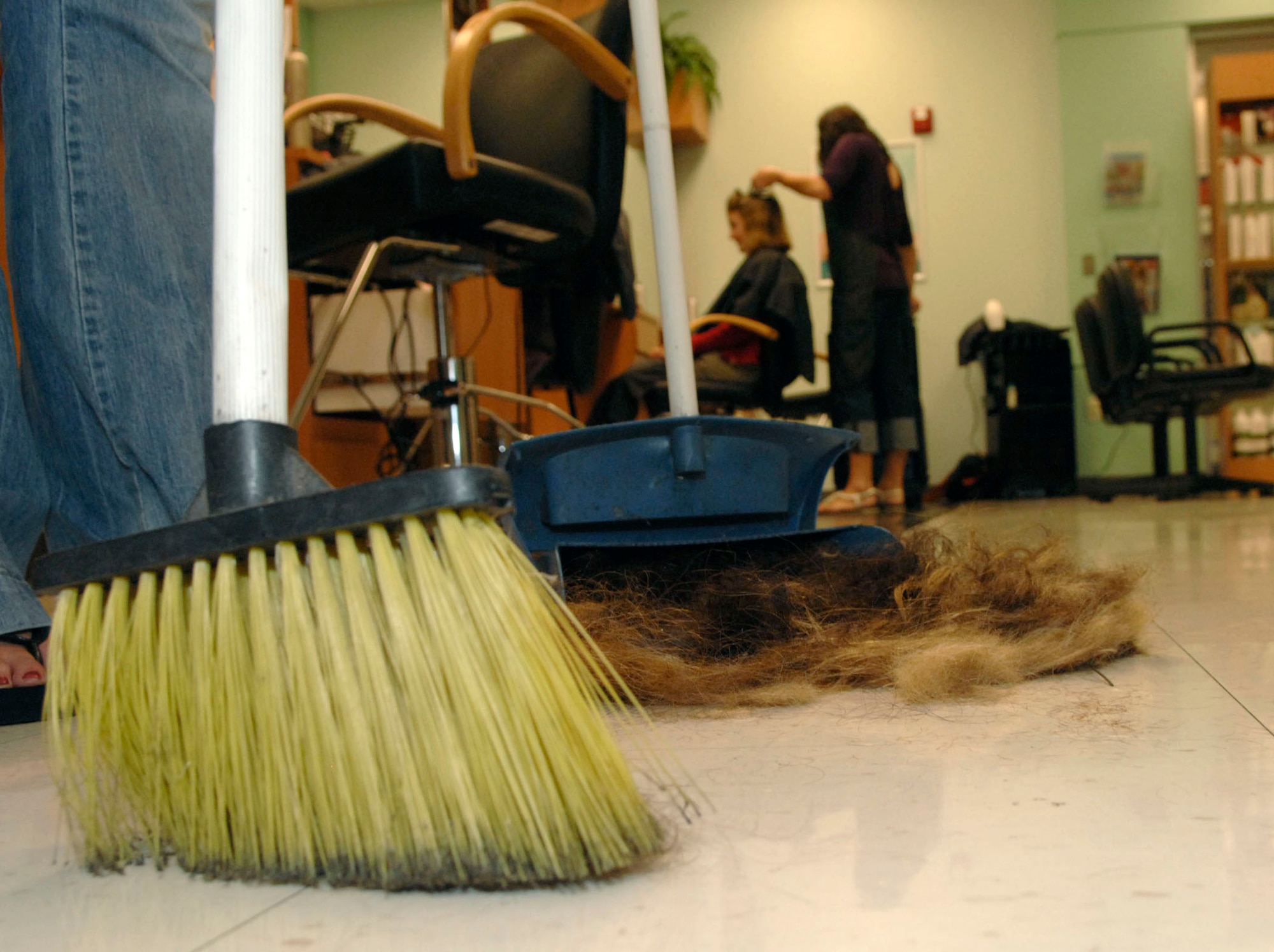 A stylist at the base exchange beauty salon collects hair clippings to be donated to an organization that makes booms to soak up oil to assist with the oil spill in the Gulf of Mexico.(Courtesy photo)
