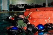 MINOT, N.D. -- Aircrew members from the 69th and 23rd Bomb Squadrons pull their wingmen to safety onto a 20 man inflatable raft during an aircrew water training course at the Minot State University pool here July 13. The refresher course helped sharpen aircrew member’s skills in order for them to be properly prepared for real world survival scenarios. The course was lead by Senior Airman Brett Steinbrink of the 5th Operations Support Squadron. Airman Steinbrink is a survive, evade, resist and escape specialist. (U.S. Air Force photo by Airman 1st Class Aaron-Forest Wainwright)