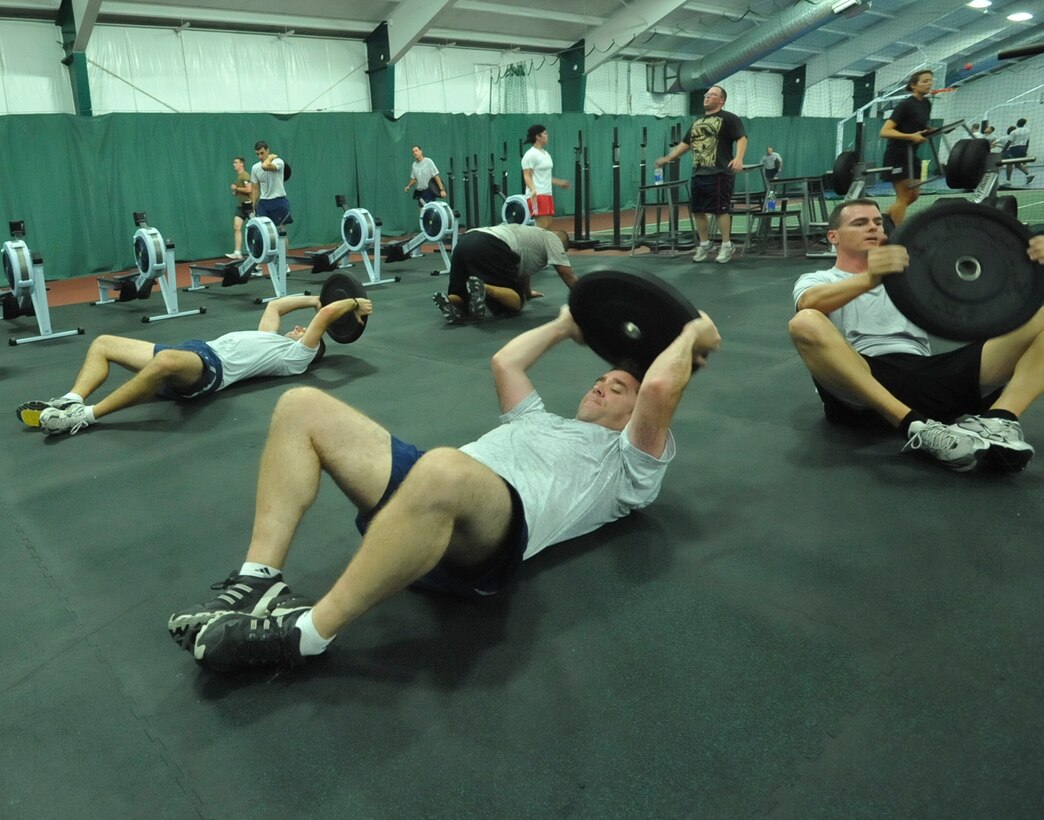 JOINT BASE ANDREWS, Md. -- A group of 89th Operation Support Squadron members perform sit-ups with 25-pound weights as a part of their modified version of CrossFit during a squadron physical fitness training session in the Tactical Fitness Center, at the West Fitness Center, July 8.  (U.S. Air Force photo by Bobby Jones)