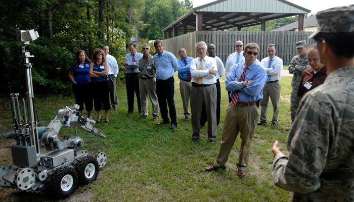 Capt. Sylvester D'Agrella briefs the Joint Base Charleston Honorary Commanders after demonstrating the Percussion Actuated Neutralizer outside the 628th Civil Engineer Squadron explosive ordnance disposal building July 14, 2010 on Joint Base Charleston, S.C. The PAN is a high-velocity, precision tool used to disrupt IEDs with water, air, or steel shots. This is the tool of choice as it allows flexible, surgical shots to be taken to prevent a detonation and preserve evidence for law enforcement officers. The honorary commanders toured EOD as part of a base orientation tour to learn more about the missions performed by different units on Joint Base Charleston. Captain D'Agrella is the commander of the 628 CES explosive ordnance disposal team. (U.S. Air Force photo/Senior Airman Timothy Taylor)