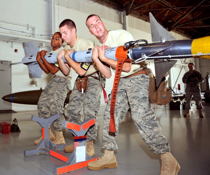 100709-F-4406D-018 SHAW AIR FORCE BASE, S.C.--    Airman 1st Class Marcus Mitchell, Airman 1st Class Steven Vierra, and Staff Sgt. Michael Delucy from the 77th Aircraft Maintenance Unit "Gamblers" all use teamwork to lift an AIM-120 missile for the Weapons Load Crew Competition in Hanger 611, July 9, 2010. In the second Weapons Load Crew of the Quarter competition this year, two crews competed to become eligible for the Load Crew of the Year and to showcase the Tech. Sgt. Charles D. Lockwood Memorial trophy. (U.S. Air Force photo/ Airman 1st Class Tabatha L. Duarte)