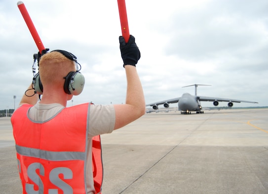 Senior Airman Michael DeNapoli, 43rd Aircraft Maintenance Squadron, marshals a C-5 for takeoff on the Pope flightline, July 13. Airman DeNapoli is a crew chief in the 43rd AMXS where he marshals, refuels, inspects and repairs enroute Air Mobility Command aircraft. (U.S. Air Force Photo/1st Lt. Cammie Quinn)