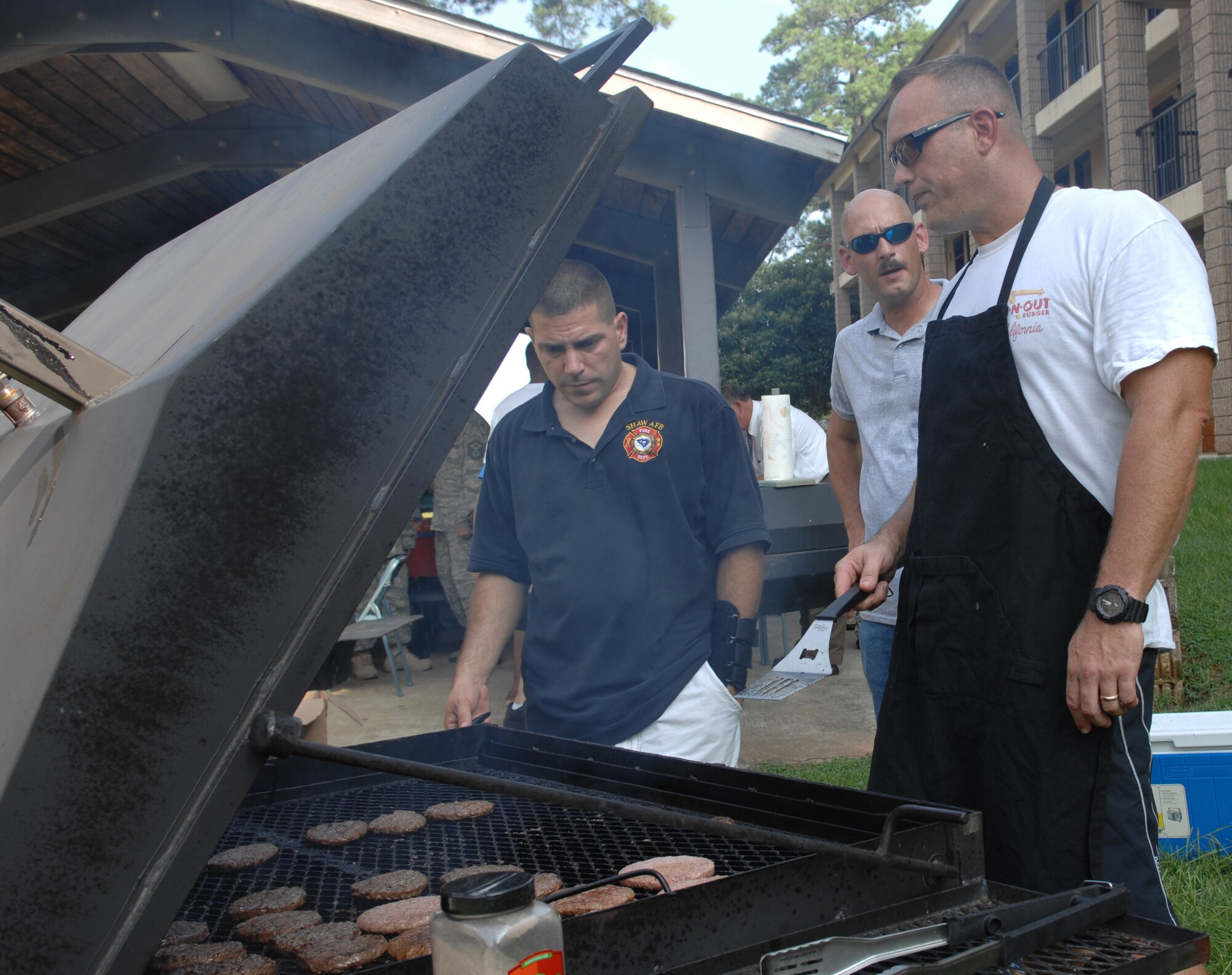 (From left to right) Senior Master Sgt. Matthew Clegg, 20th Civil Engineering Squadron deputy fire chief, Senior Master Sgt. Jerry Dire, 20th Communications Squadron systems superintendent, and Master Sgt. Mike Jordan, U.S. Air Forces Central A2 division non-commissioned officer in charge, grill burgers for the dorm dinner here, July 13, 2010. The dorm dinner is usually held the second Tuesday of each month. (U.S. Air Force photo/ Airman 1st Class Alexandria Mosness)