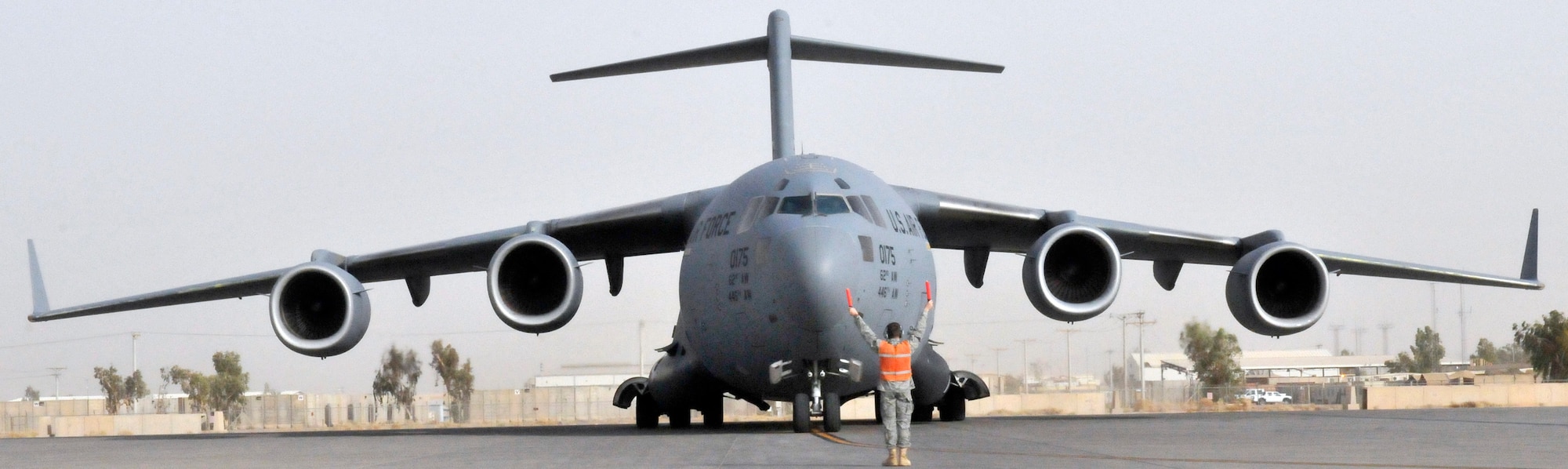 Airman 1st Class Robert Jacoby, 521st Air Mobility Operations Group, Detachment 5 communication-navigation equipment maintainer, marshals a C-17 Globemaster III into its parking spot July 12, 2010, Joint base Balad, Iraq. From the ground to the top of the vertical stabilizer, the C-17 is five stories tall. Airman Jacoby, a native of Athens, Ala., deployed from Joint Base McGuire-Dix-Lakehurst, N.J. (U.S. Air Force photo/Staff Sgt. Phillip Butterfield)