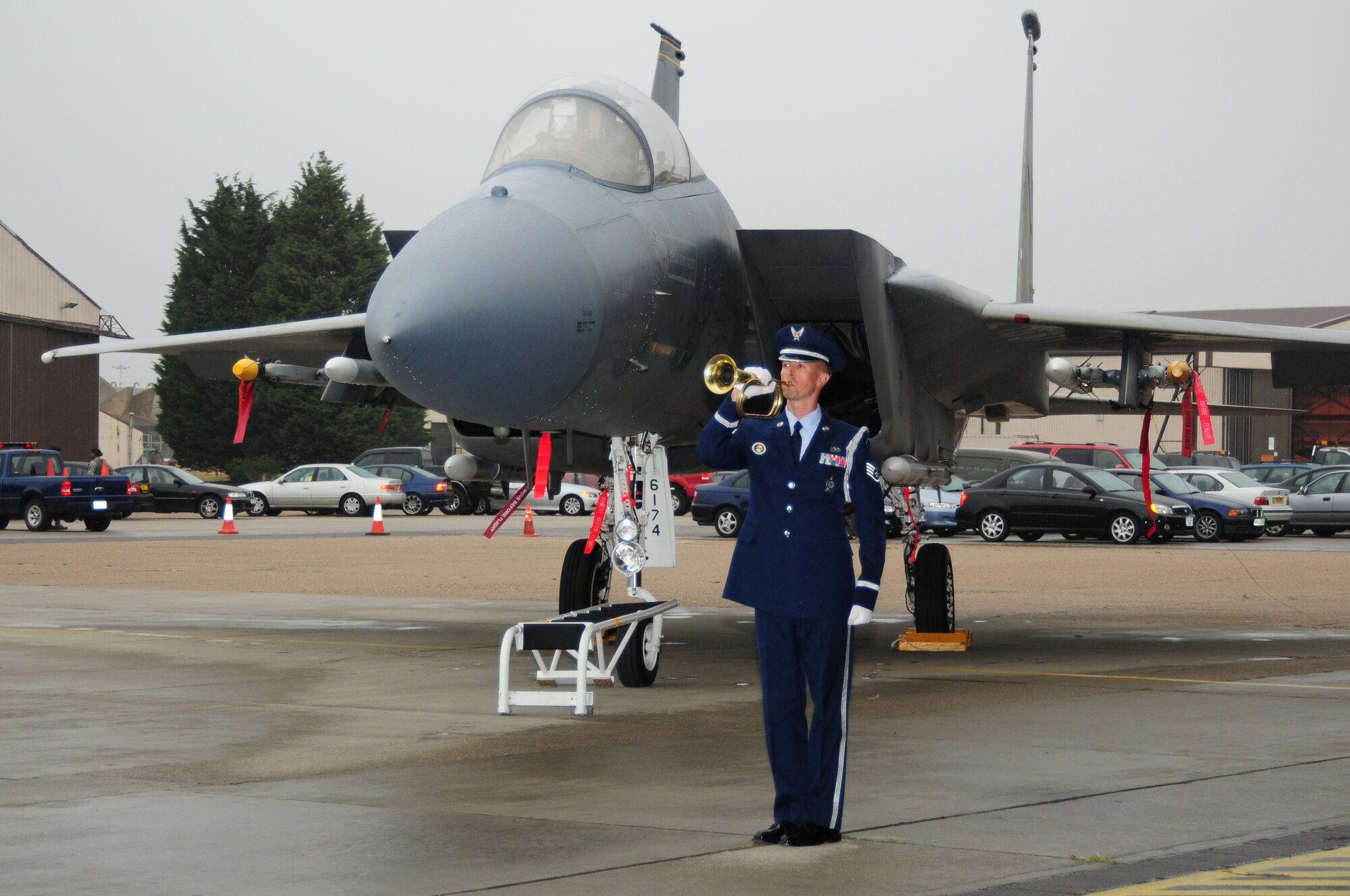 A bugler plays Taps at the memorial service for Capt. Samuel Robertson July 13 on RAF Lakenheath, England. The F-15 in the background was the aircraft Captain Robertson, who suddenly passed away July 7, flew for the 493rd Fighter Squadron. (U.S. Air Force photo/Airman 1st Class Lausanne Morgan)