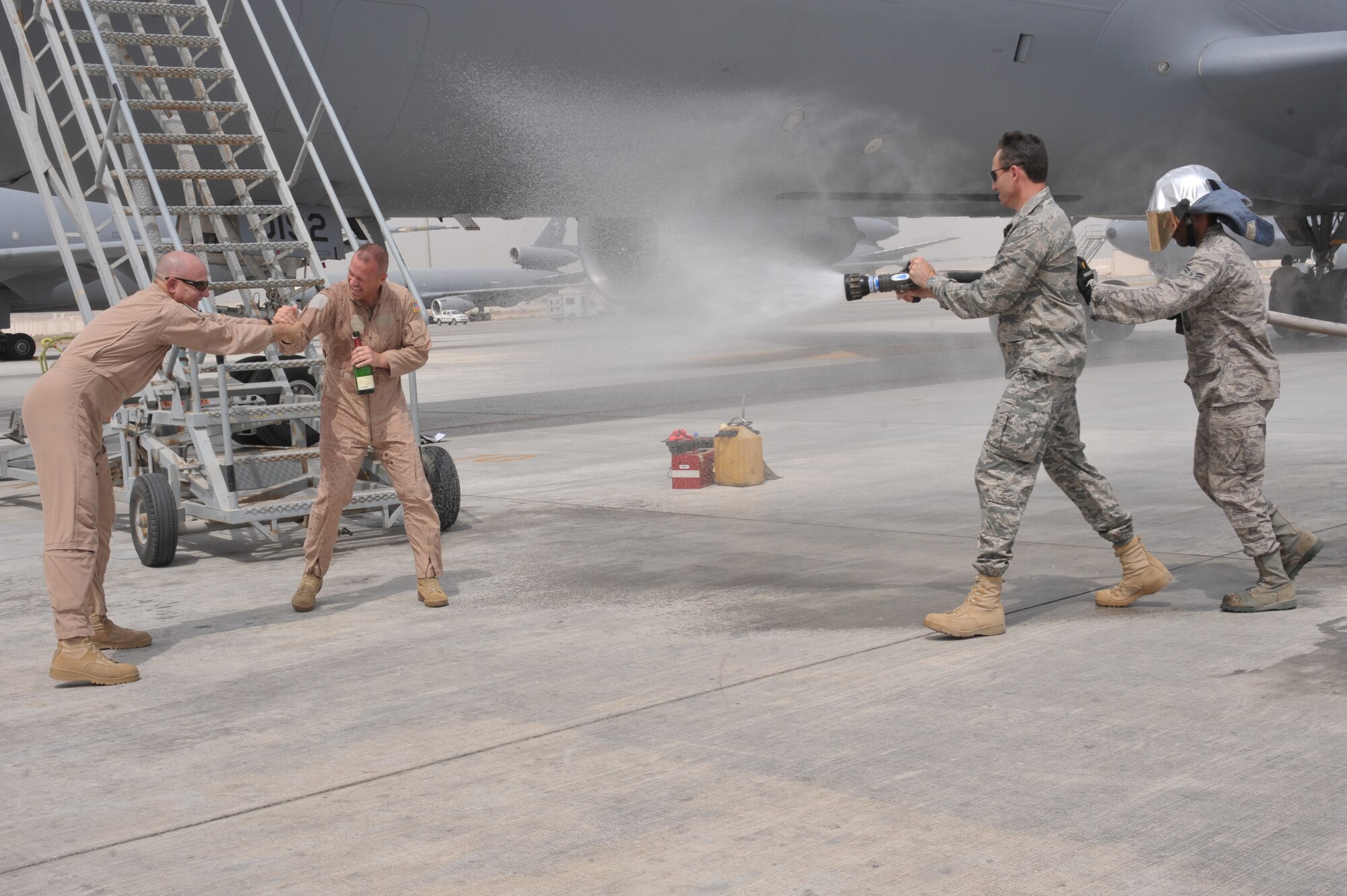 Col. Kip Turain, 380th Air Expeditionary Wing vice commander, is held by Lt. Col. James Shaw, 908 Expeditionary Air Refueling Squadron commander, while Brig. Gen. Mike Minahan, 380th Air Expeditionary Wing Commander, sprays him with a fire hose after his fini flight July 13 at an undisclosed location in Southwest Asia. (U.S. Air Force Photo/Tech Sgt April Wickes )

