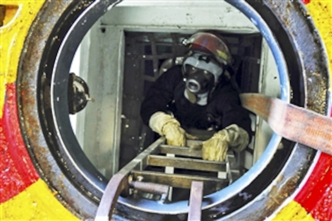 U.S. Navy Seaman Cory Thomas emerges from an emergency escape scuttle after setting smoke boundaries during a fire drill aboard the USS Wasp in the Atlantic Ocean, July 13, 2010. 