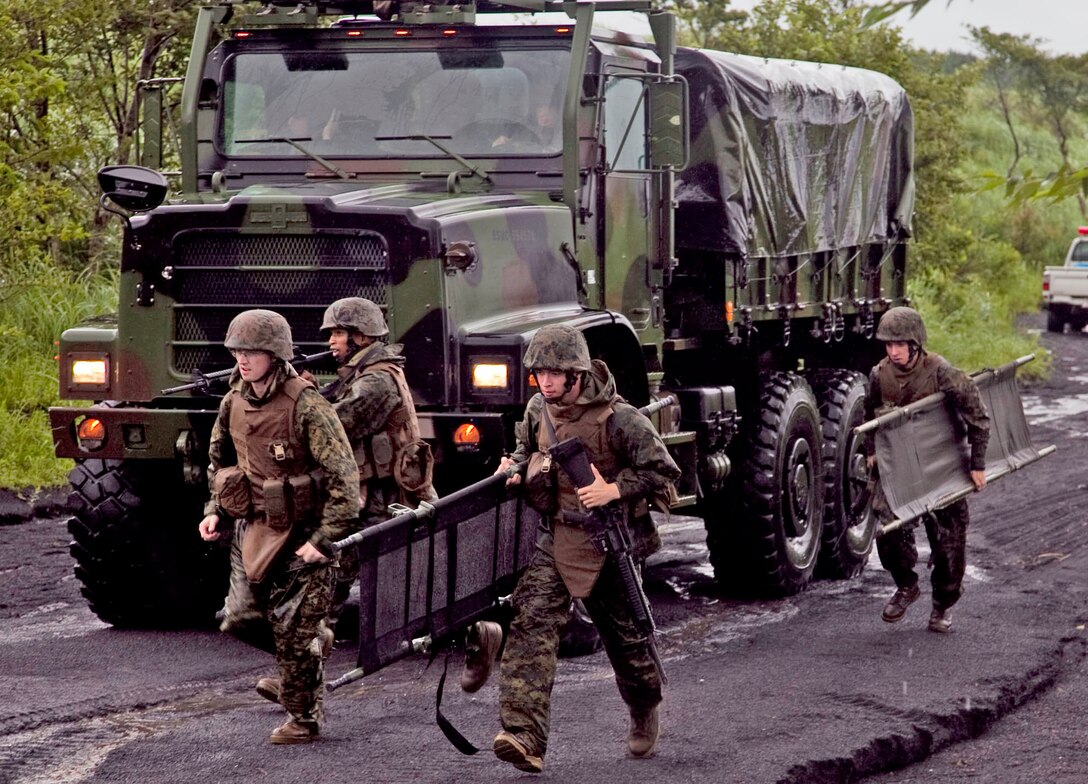 Marines and a Navy Corpsman run to aid wounded victims during exercise Dragon Fire at the Combined Arms Training Center Camp Fuji, Japan July 14. Dragon Fire is an annual exercise Combat Logistics Company 36 Marines conduct in order to execute combat military operations.