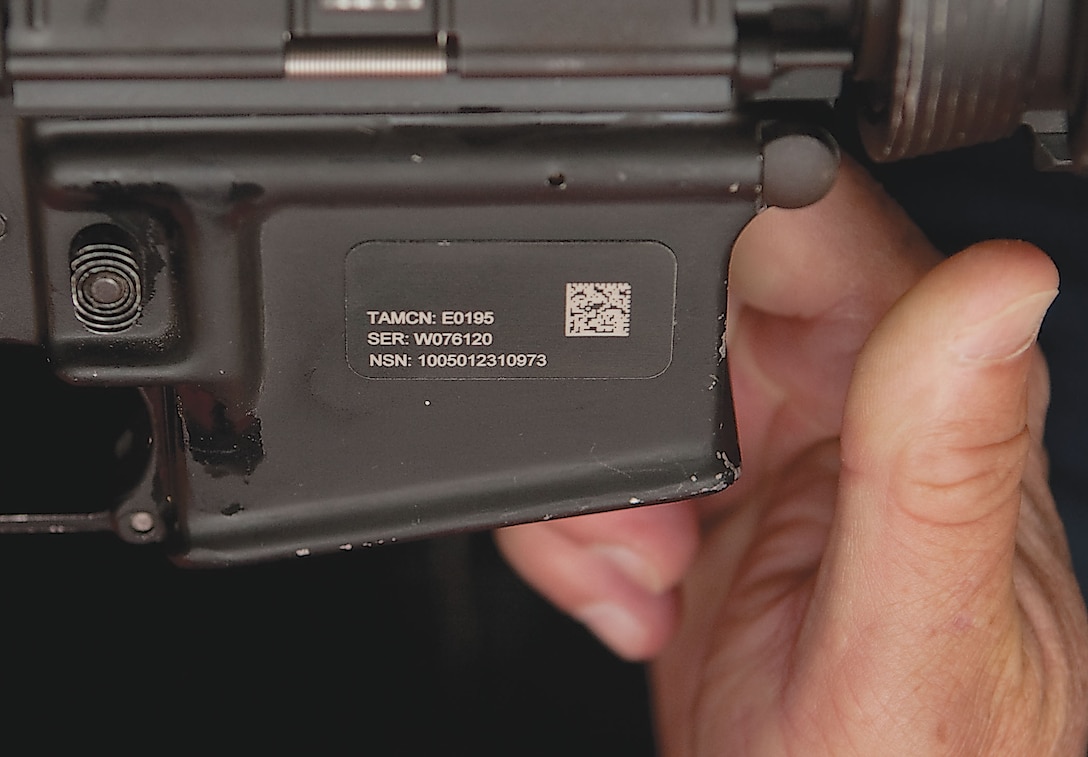 A new Item Unique Identification tag is placed on a rifle inside the 3rd Radio Battalion armory by the IUID marking team July 14.