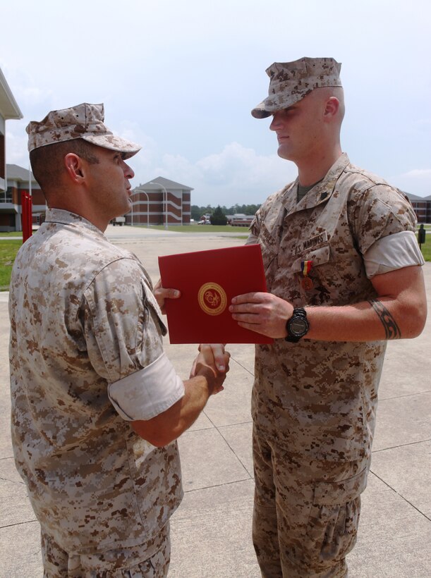 Sgt. William Holls, (right) a combat instructor with Mobile Training Company, Advanced Infantry Training Battalion, School of Infantry – East, is presented the Navy and Marine Corps Medal by Lt. Col. John Armellino, commanding officer of AITB, SOI – E, during a ceremony held aboard Camp Geiger, July 15, for saving a Marine’s life while conducting training in the grenade pit in September 2009.