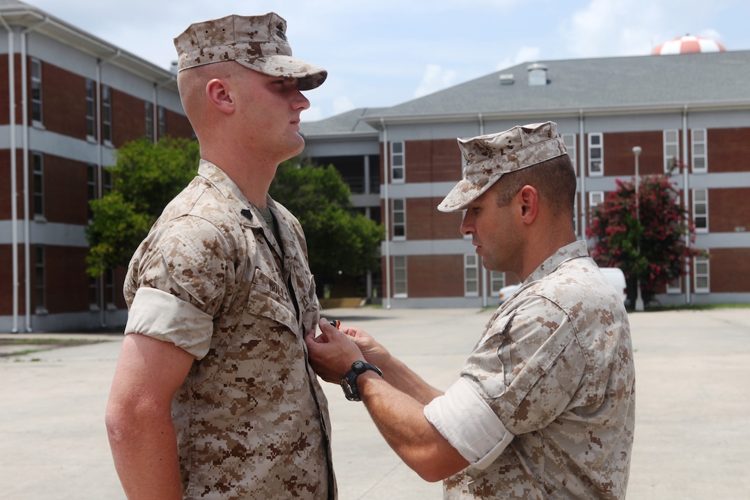Sgt. William Holls, (left) a combat instructor with Mobile Training Company, Advanced Infantry Training Battalion, School of Infantry – East, is presented the Navy and Marine Corps Medal by Lt. Col. John Armellino, commanding officer of AITB, SOI – E, during a ceremony held aboard Camp Geiger, July 15, for saving a Marine’s life while conducting training in the grenade pit in September 2009.