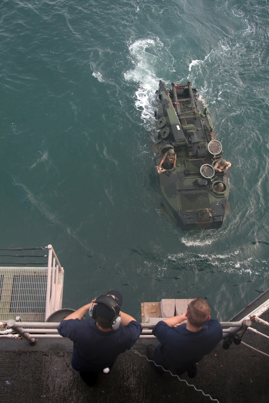 Two Sailors aboard the USS Iwo Jima watch as Marines embark an Amphibious Assault Vehicle into the ship's well deck, July 15. The Marines are from Company A, 2nd Assault Amphibian Battalion and are participating in a four-month deployment to Central and South America in support of Continuing Promise 2010.   ::r::::n::