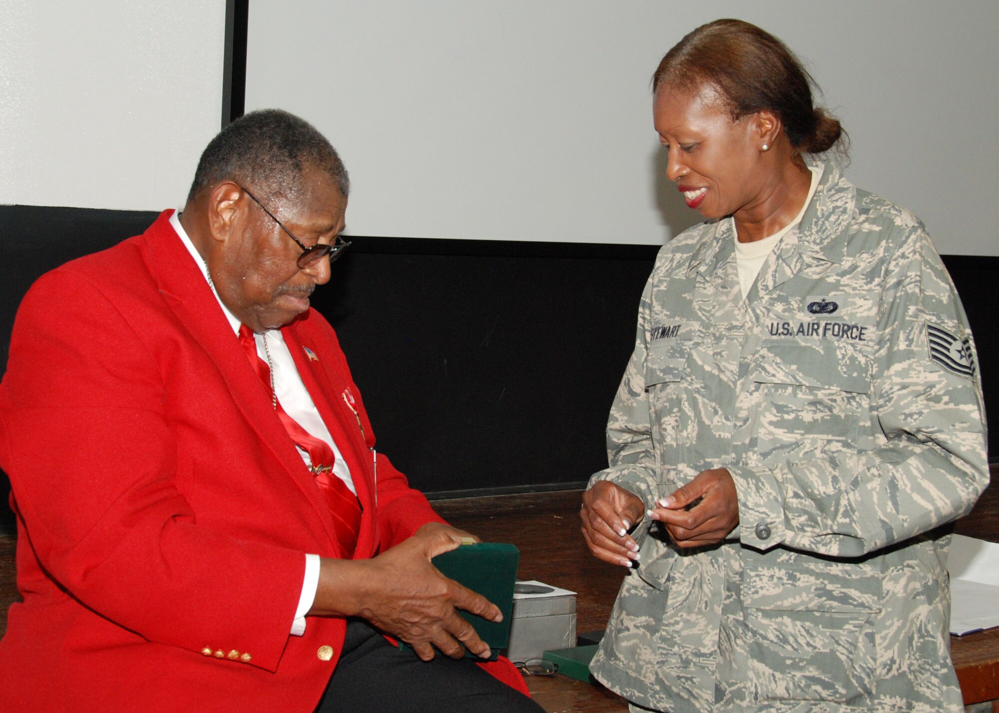 Retired Chief Master Sgt. Walter Richardson shows his Congressional Gold Medal to Tech. Sgt. Glenda Stewart, 919th Mission Support Group, inside the Duke Field base theater July 10.  An original member of the famed World War II-era Tuskegee Airmen, the 30-year veteran later spoke to a mass audience of 919th Special Operations Wing reservists about his role as one of the first African-American Airmen tasked to begin integrating the fledgling U.S. Air Force.   (U.S. Air Force photo/Tech. Sgt. Cheryl Foster)