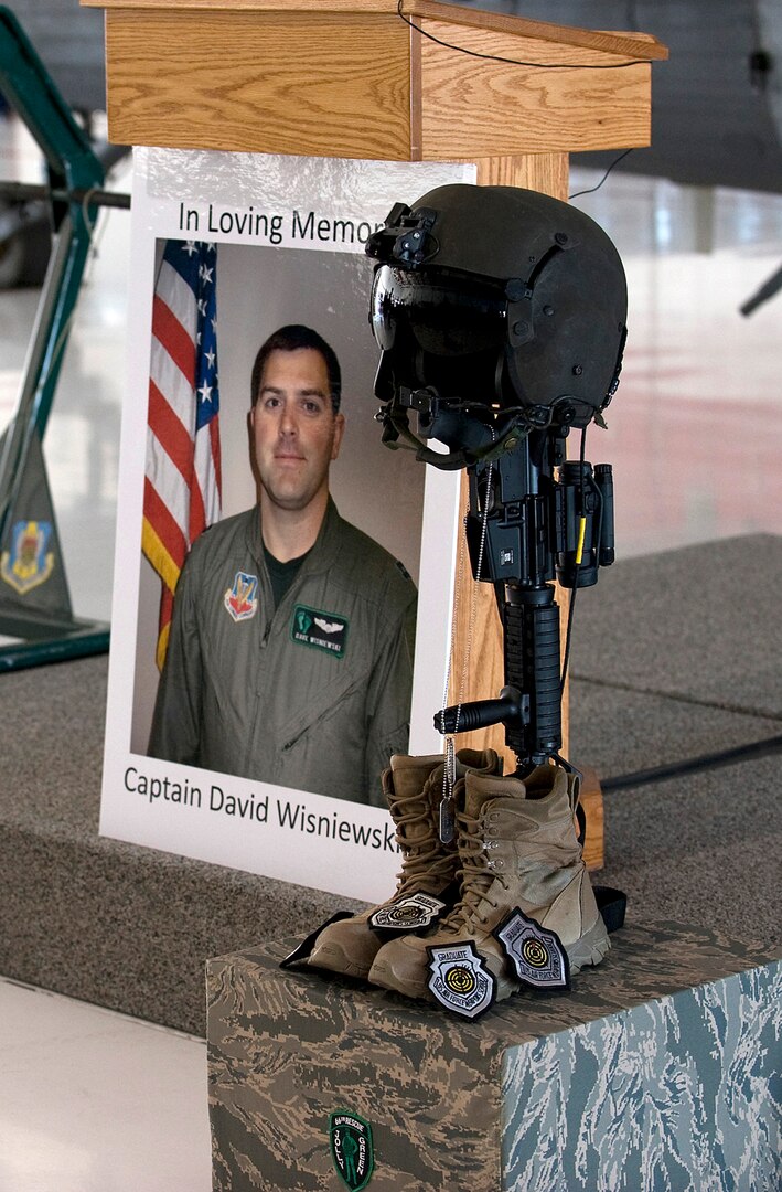 NELLIS AIR FORCE BASE, Nev. --  A photo of Capt. David Wisniewski stands next to a battle cross in his honor during a memorial service at Nellis Air Force Base July 15.  Captain Wisniewski, 31, was an HH-60G Pave Hawk helicopter pilot assigned to the 66th Rescue Squadron.  He passed away at the National Naval Medical Center in Bethesda, Md., July 2 from injuries received when an HH-60G Pave Hawk helicopter crashed in southeastern Afghanistan June 9. Four other Airmen killed and two others were wounded during the incident. (U.S. Air Force Photo by Airman 1st Class Brett Clashman)

