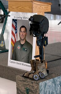 NELLIS AIR FORCE BASE, Nev. --  A photo of Capt. David Wisniewski stands next to a battle cross in his honor during a memorial service at Nellis Air Force Base July 15.  Captain Wisniewski, 31, was an HH-60G Pave Hawk helicopter pilot assigned to the 66th Rescue Squadron.  He passed away at the National Naval Medical Center in Bethesda, Md., July 2 from injuries received when an HH-60G Pave Hawk helicopter crashed in southeastern Afghanistan June 9. Four other Airmen killed and two others were wounded during the incident. (U.S. Air Force Photo by Airman 1st Class Brett Clashman)

