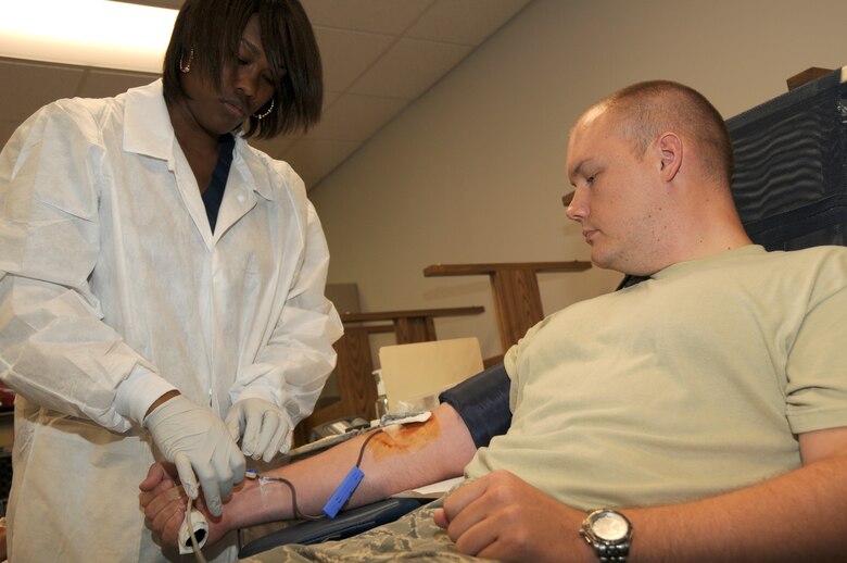 Raeisha Clay, Collection Technician, connects tubes to Senior Airman Seth Waple from the 175th Wing, Maryland Air National Guard, in order to collect blood during an American Red Cross blood drive at Warfield Air National Guard Base, Baltimore, Maryland, July 15, 2010.  Members of the 175th volunteered throughout the day to donate 24 pints of blood to the Red Cross. (U.S. Air Force photo by Tech. Sgt. Chris Schepers/Released)