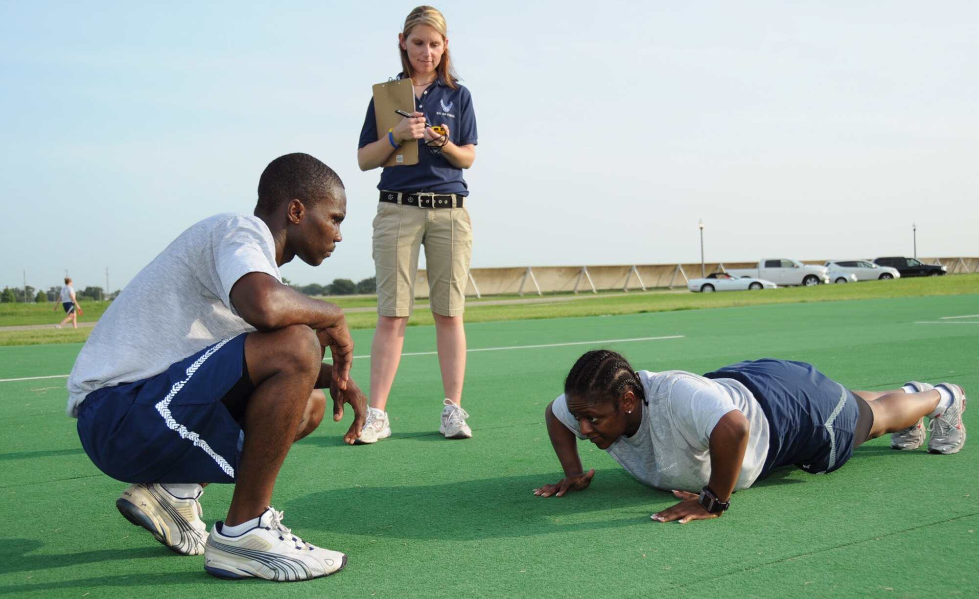 Staff Sgt. Kwadwo Agyen-Frempong, left, 335th Training Squadron, counts pushups for Tech. Sgt. Lisa Jackson, Airman Leadership School instructor, as Kristina Brinkmeier, 81st FSS, assesses Sergeant Jackson’s fitness performance.  (U.S. Air Force photo by Kemberly Groue)