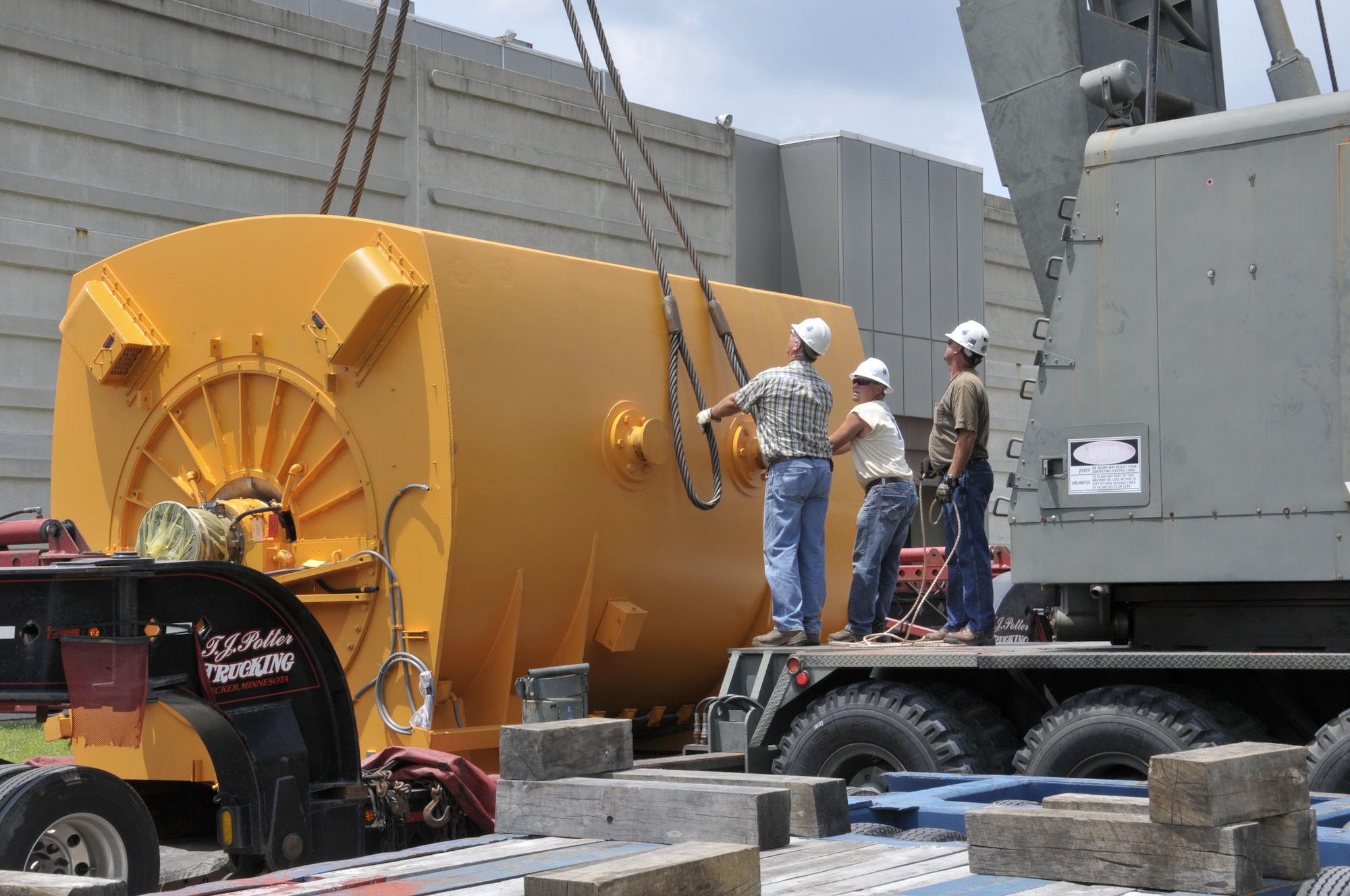 ATA Riggers Wayne Brown and ATA Truck Driver Jeff Youngblood attach a guideline to the sling assembly in preparation to lift a large electric motor off the Electric Machinery Company 13-axle trailer. (Photo by Rick Goodfriend)