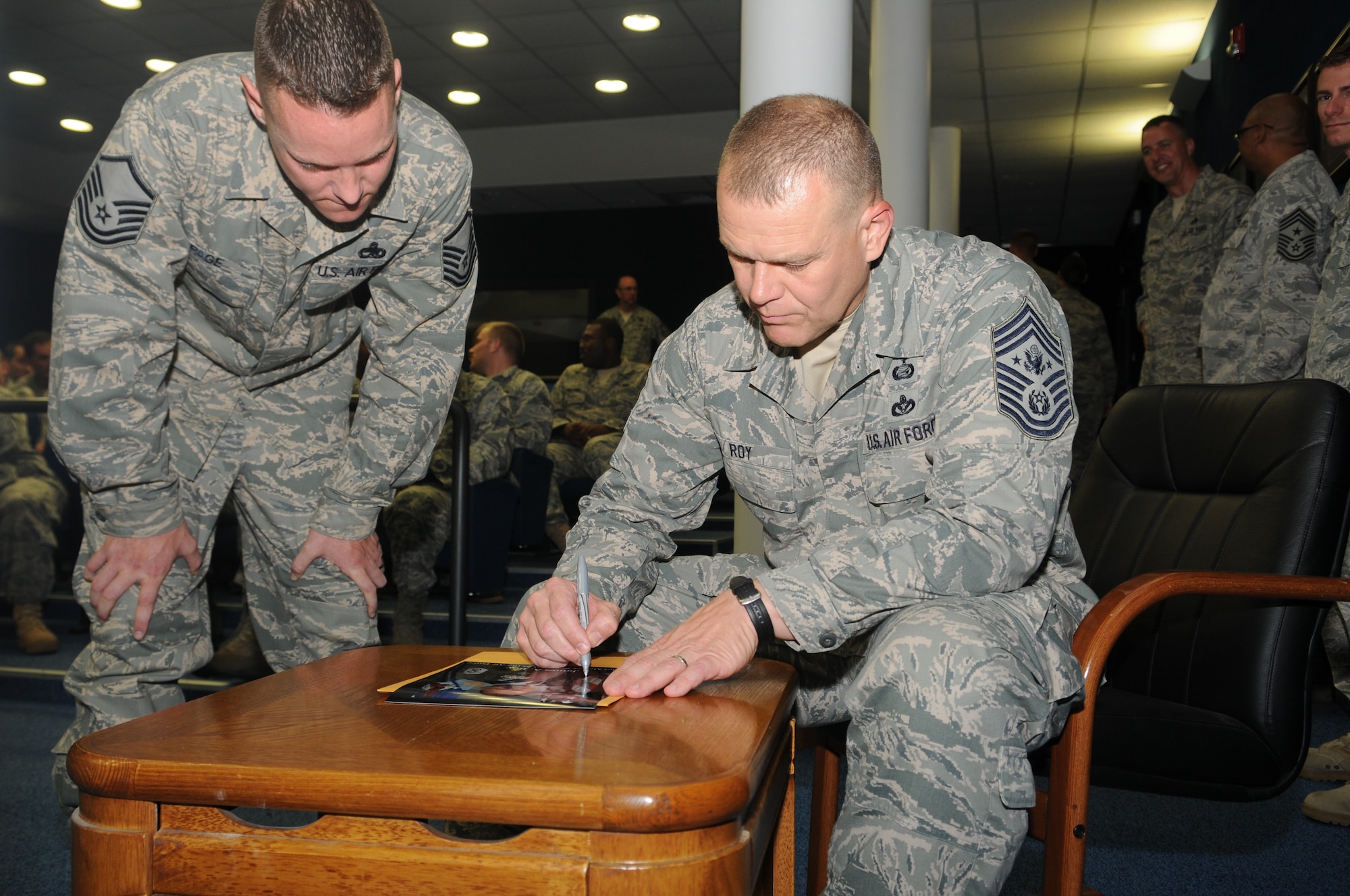 Chief Master Sgt. of the Air Force James Roy signs his photograph for Master Sgt. Michael Page, Airman Leadership School commandant, during the chief’s visit to Aviano July 9. While at Aviano, Chief Roy visited the Radar Approach Control, Explosive Ordnance Disposal unit, Air Mobility Command Terminal, 31st Medical Group clinic, 31st Civil Engineer Squadron compound and 31st Security Forces Squadron Armory. (U.S. Air Force photo/Staff Sgt. Nadine Barclay)