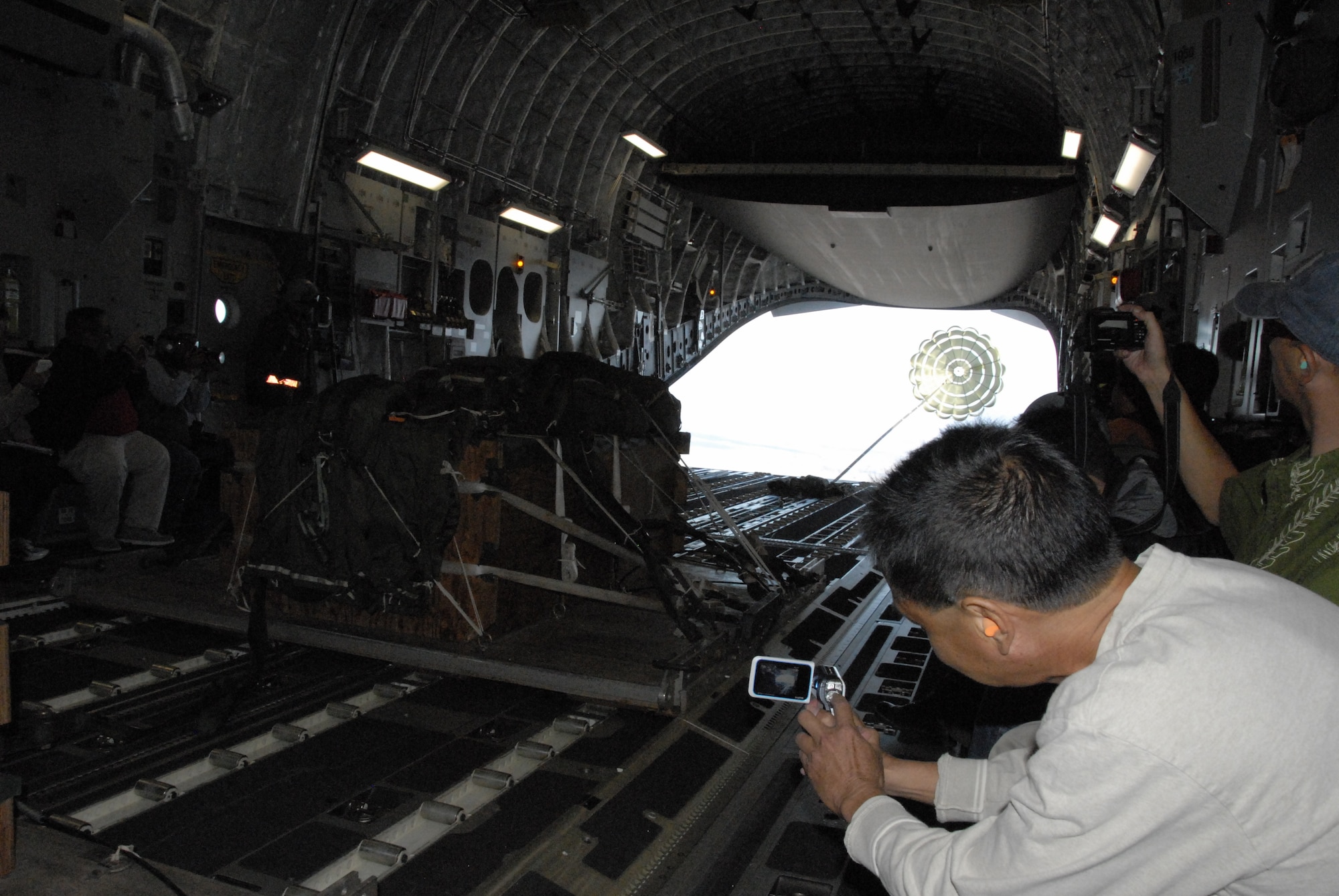 Burt Lum photographs an air drop in a C-17 Globemaster III July, 16, 2010 over a simulated forward operating base in Hawaii. Mr. Lum is a social media from Hawaii Public Radio. (U.S. Air Force photo/Tech. Sgt. Matthew McGovern)