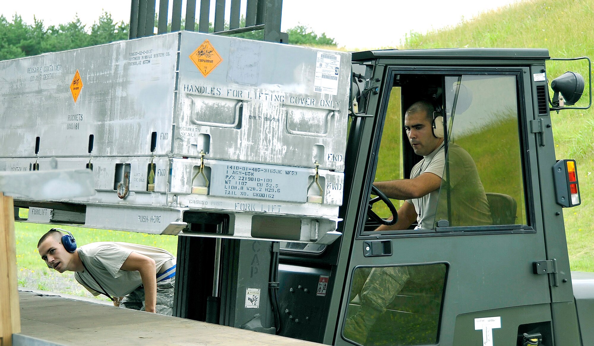 Airman Mason Hidde spots as Airman 1st Class Emanuel Sanchez loads munitions onto a flatbed truck July 13, 2010, at Misawa Air Base, Japan.  Airmen there moved more than 700 tons of munitions in an effort to dispose of unserviceable and unused items.  The Airmen are munitions systems specialists with the 35th Maintenance Squadron.  (U.S. Air Force photo/Staff Sgt. Chad C. Strohmeyer)