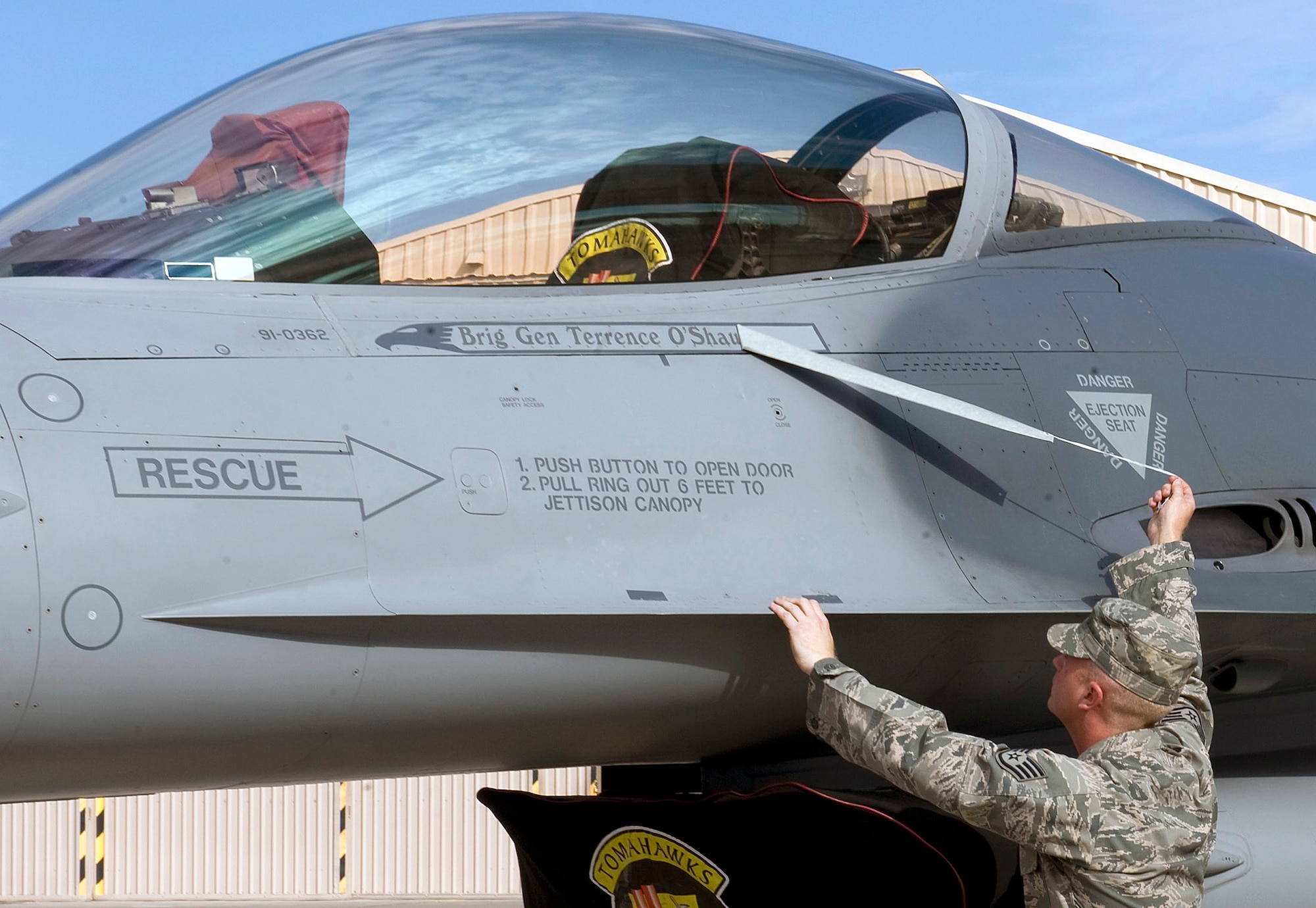 NELLIS AIR FORCE BASE, Nev.-- Staff Sgt. Jeremy Strivens, 57th Aircraft Maintenance Squadron crew chief, removes tape from an F-16 Fighting Falcon with the name of Brig. Gen. Terrence O'Shaughnessy, the new 57th Wing commander, at a change of command ceremony July 16. The 57th Wing is responsible for 38 squadrons at 12 installations, constituting the Air Force's most diverse flying wing, flying and maintaining more than 130 aircraft. The 57th Wing also oversees the U.S. Air Force Weapons School; U.S. Air Force Air Demonstration Squadron, the Thunderbirds; and the Red Flag and Green Flag exercises. (U.S. Air Force Photo by Airman 1st Class Brett Clashman)