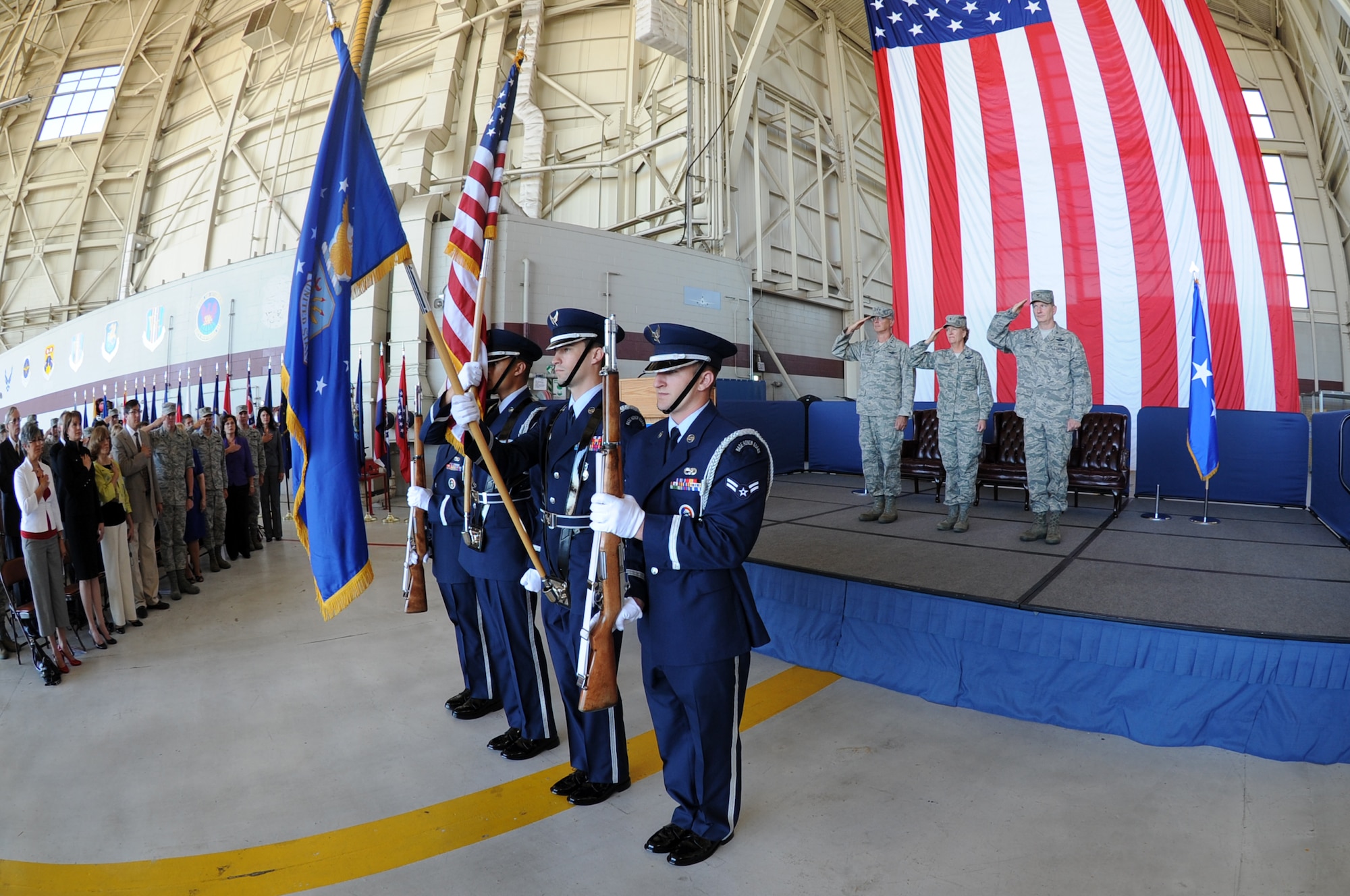 The Travis Honor Guard present the colors at the 15th Expeditionary 
Mobility Task Force change of command while left to right, Lt. G. Robert R. Allardice, 18th Air Force commander, Brig. Gen. Barbara J. Faulkenberry, outgoing 15th EMTF  commander and Col. Robert D. Thomas, incoming 15th EMTF commander, render honors to the flag during the national anthem prior to the 15th EMTF change of command ceremony  July 15th.  (U.S. Air Force photo by Civ/Nan Wylie)
