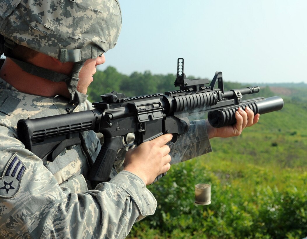 Senior Airman Garren Holcomb, 316th Security Forces Squadron patrolman, clears a practice round out of a M203 grenade launcher at Marine Corps Base Quantico, July 15, 2010.  Members qualifying fire 15 practice rounds that emit an orange smoke so that the 316th SFS combat arms instructors can assist in getting a more accurate aim. (U.S. Air Force photo by Senior Airman Melissa V. Brownstein)