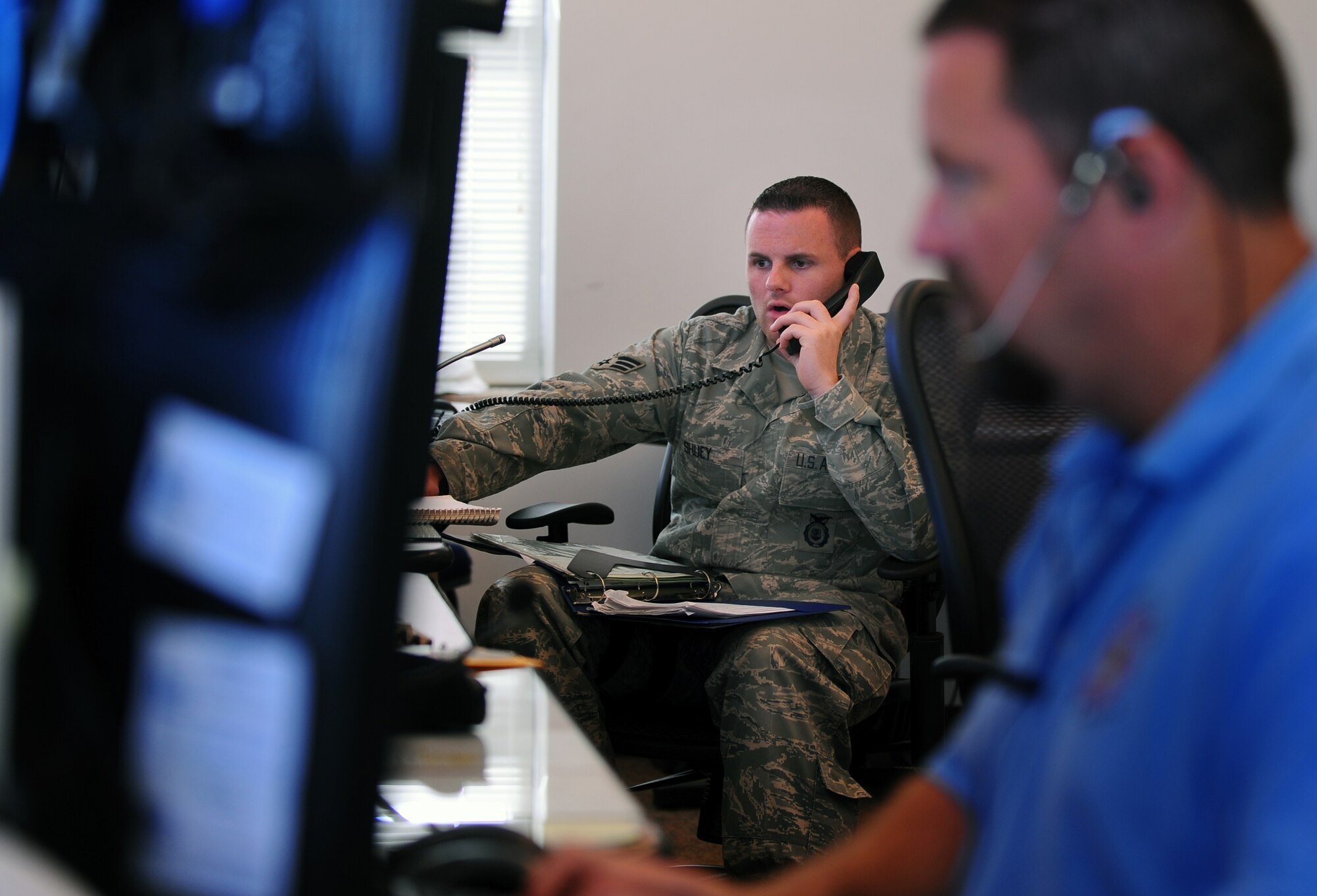 OFFUTT AIR FORCE BASE, Neb. - Senior Airman Jeremy Shuey, an Emergency Communications Center alarm monitor with the 55th Security Forces Squadron, takes a variety of calls while manning one of the phones in the new Emergency Communications Center here July 15.  The ECC was stood up June 29, placing both fire and law enforcement dispatches in a central location to create stronger situational awareness between the two departments. U.S. Air Force photo by Josh Plueger
