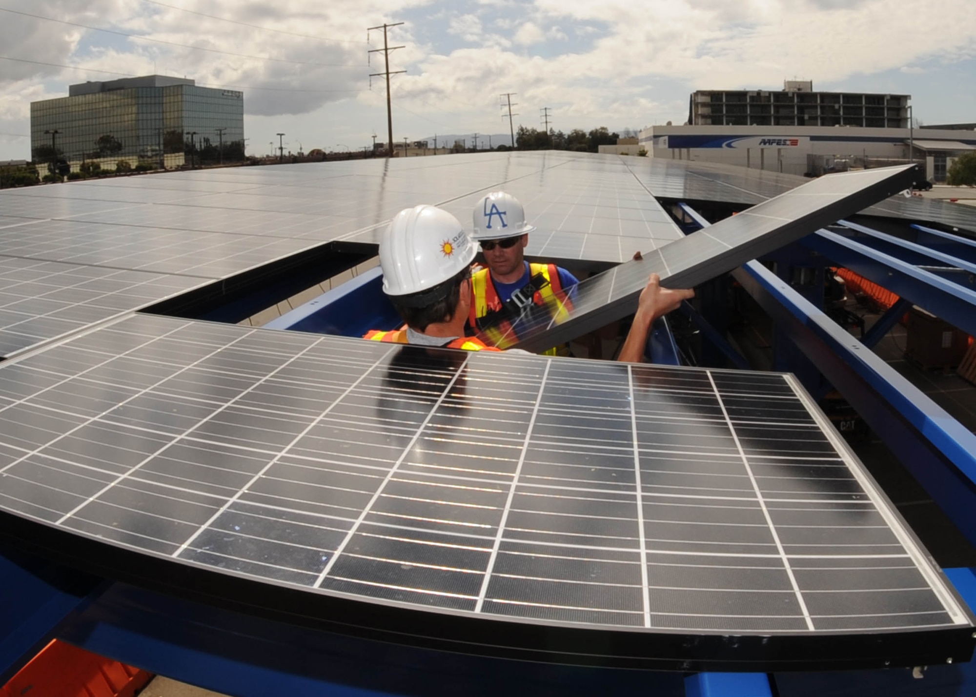 Work continues on the solar panels being installed on Los Angeles Air Force Base, Calif. When completed, the panels will decrease the amount of electricity the base purchases from the local power company. A similar project on the roof of the base commissary converts sunshine into about 290 kilowatt-hours of electricity each day, enough to power 10 typical households. (U.S. Air Force photo/Lou Hernandez)