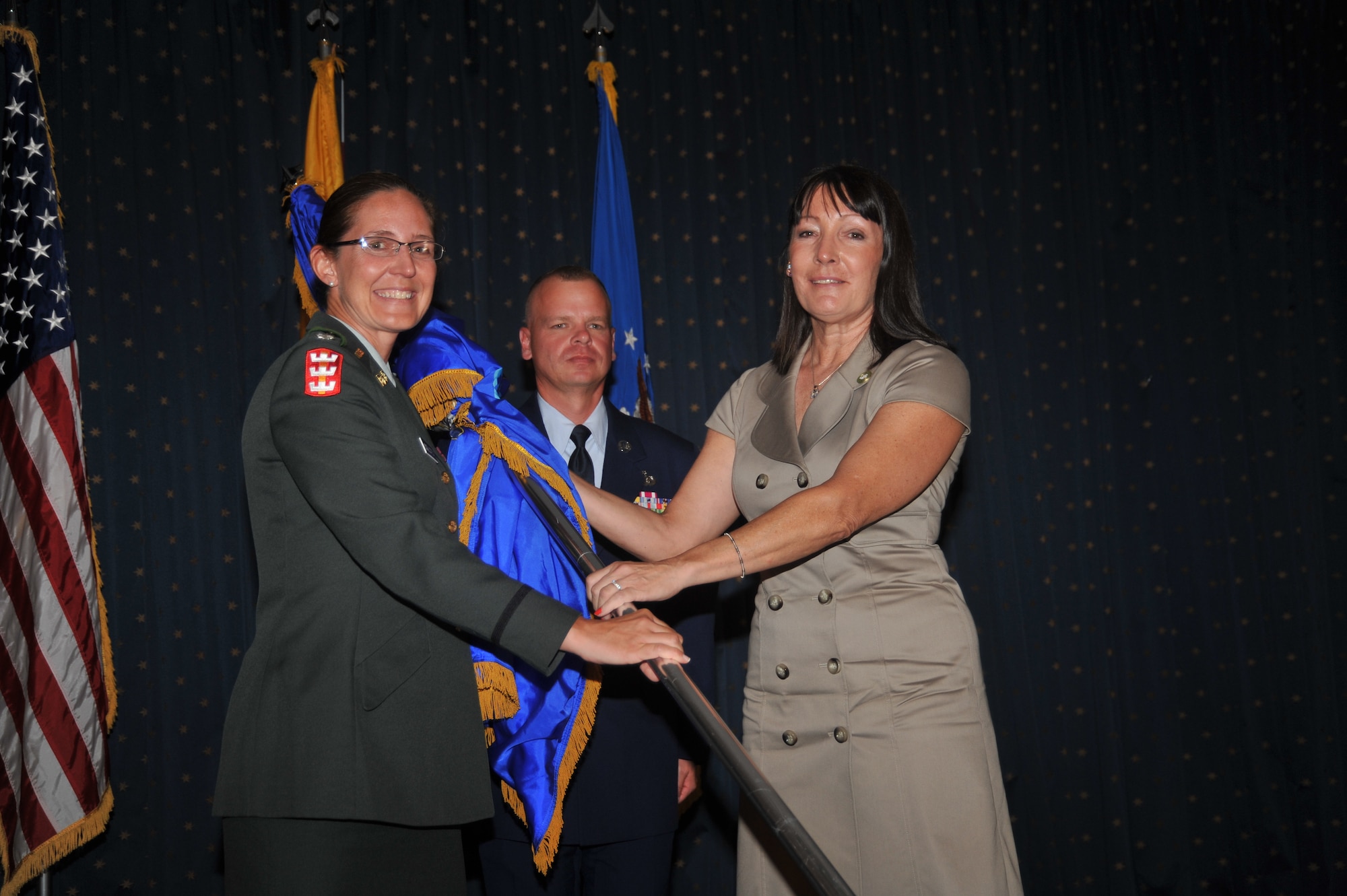 Army Lt. Col. Kimberly Colloton, U.S. Army Corps of Engineers, passes the guidon to Christine Glidden, partner/president of Ornamental and Architectural Metal Fabrication, installing her as an honorary commander.  U.S. Air Force Photo by Todd Berenger.