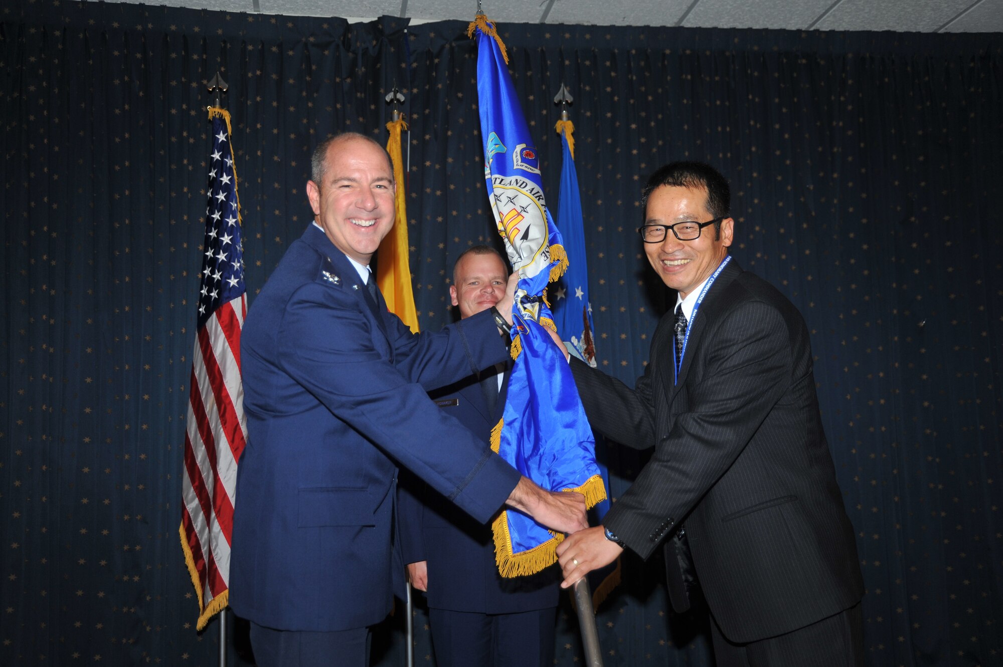 Col. James Eck, Air Force Operational Test and Evaluation Center vice commander, passes the guidon to Dr. Sang Kim, president/CEO of Turtle Press Corp. U.S. Air Force Photo by Todd Berenger.