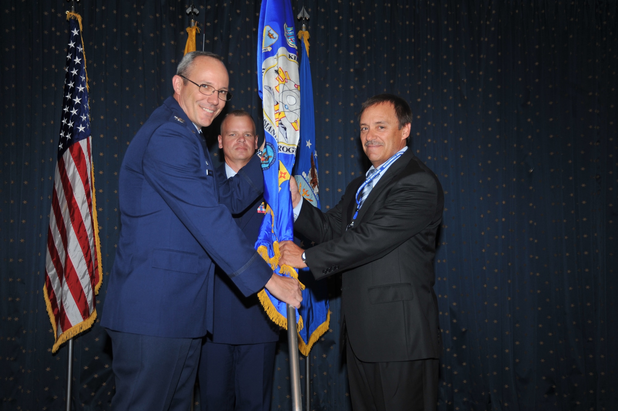 Col. Robert L. Maness, 377th Air Base Wing commander, passes the guidon to his honorary commander, John Garcia, director of Albuquerque Economic Development Department, July 9 at the Mountain View Club. U.S. Air Force Photo by Todd Berenger.